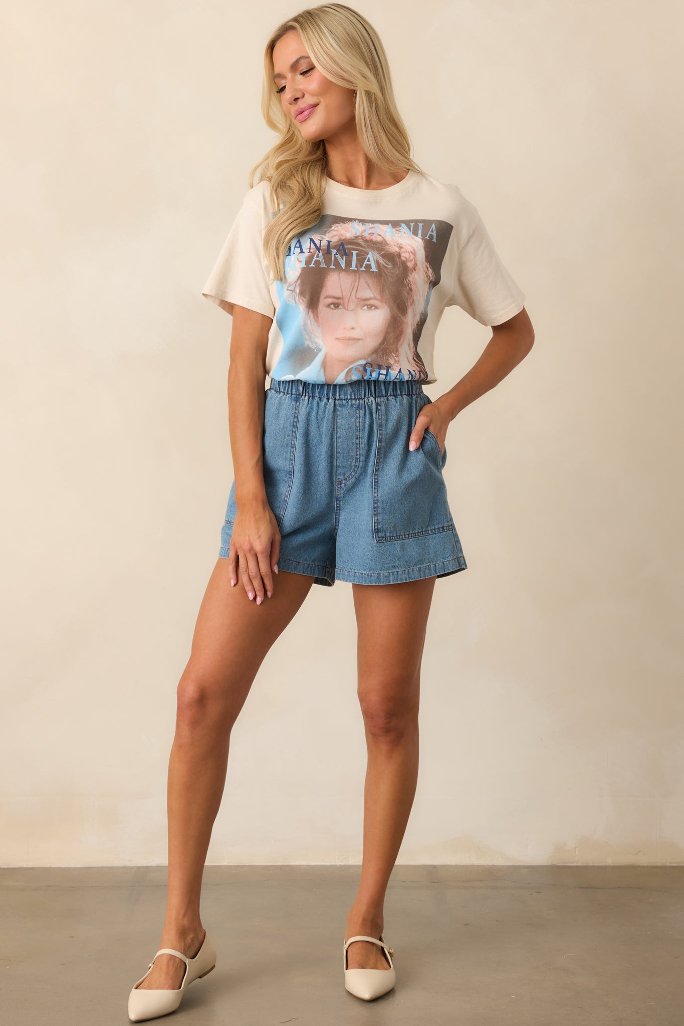 Front view of medium wash denim shorts made from 100% cotton, featuring a fully elastic waistband, faux zipper closure, and relaxed fit.