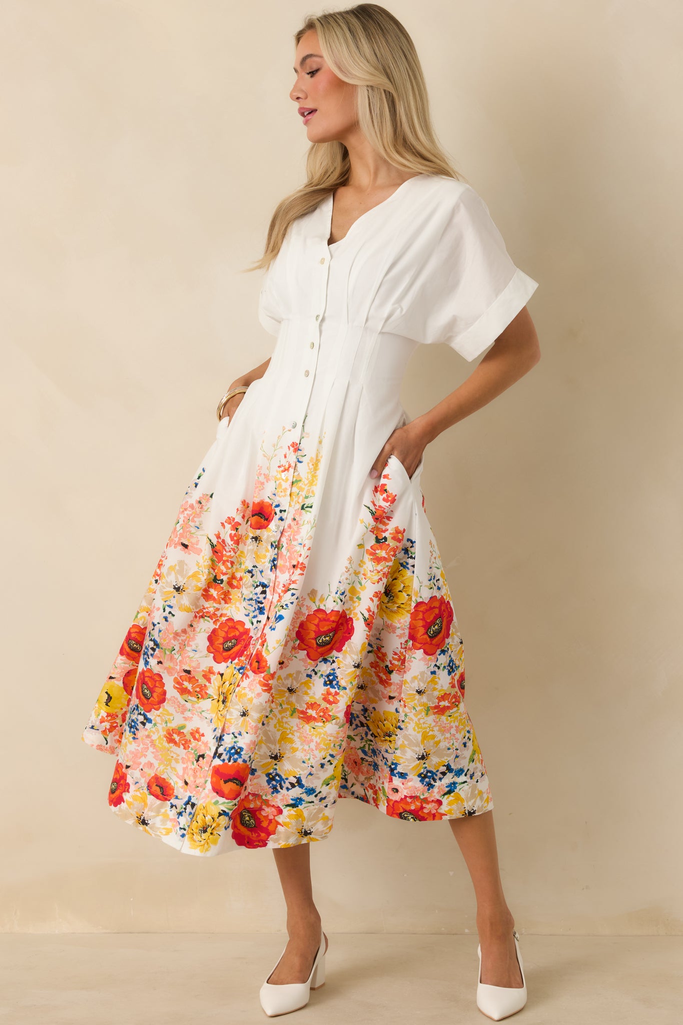 White cotton midi dress designed with a flattering V-neck, soft flutter sleeves, and an airy skirt finished with a floral border.