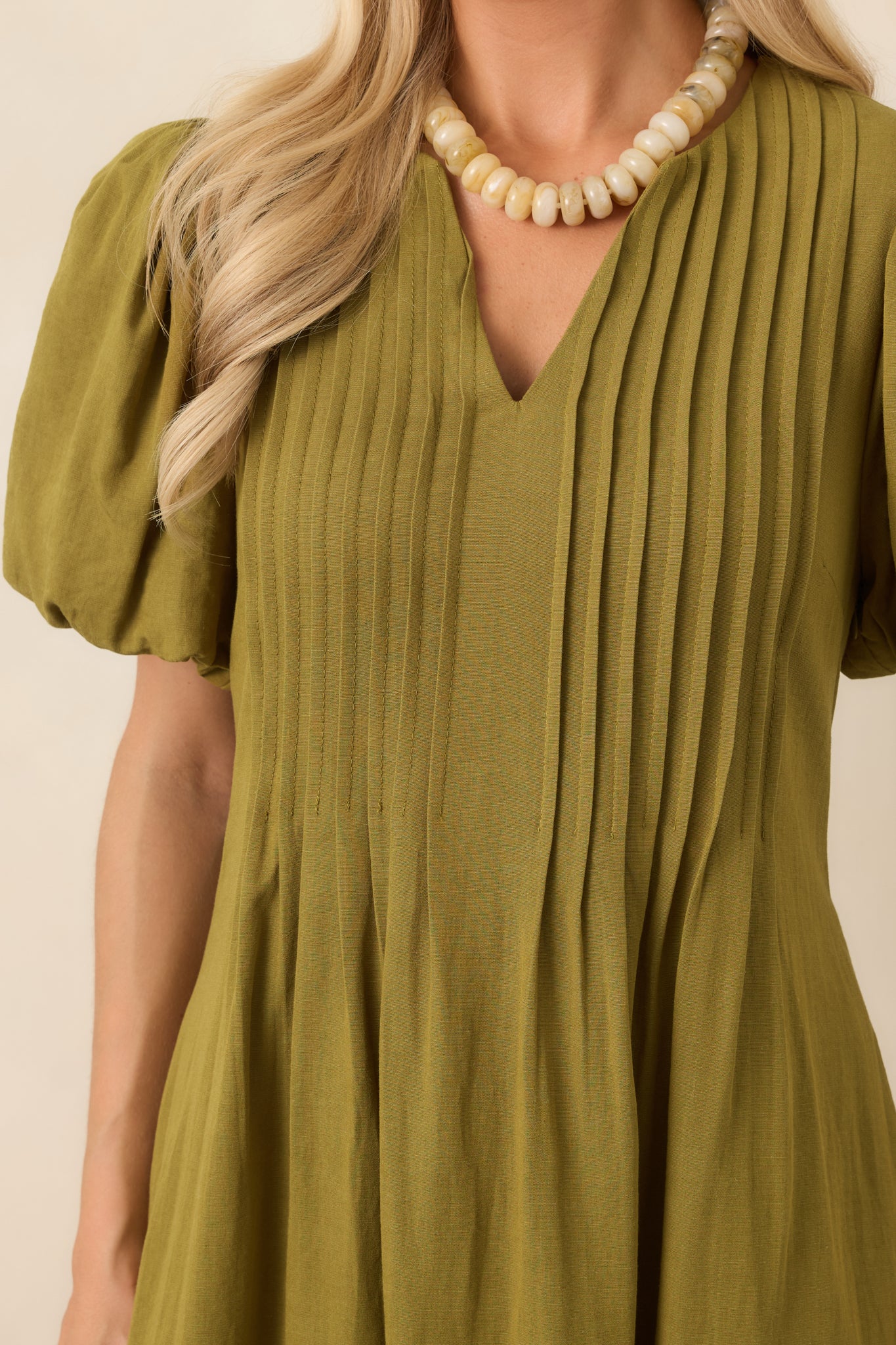 Close-up of the textured midi dress highlighting the V-neckline, intricate pintuck detailing, softly gathered sleeve fabric, and lightweight weave.