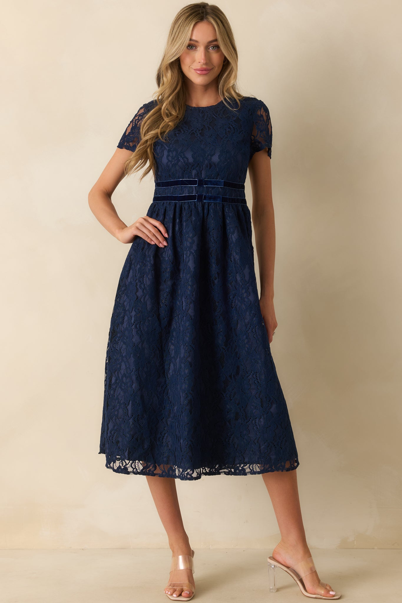 Midi-length navy dress featuring a round neckline, short sleeves, and layered lace texture for a refined finish.