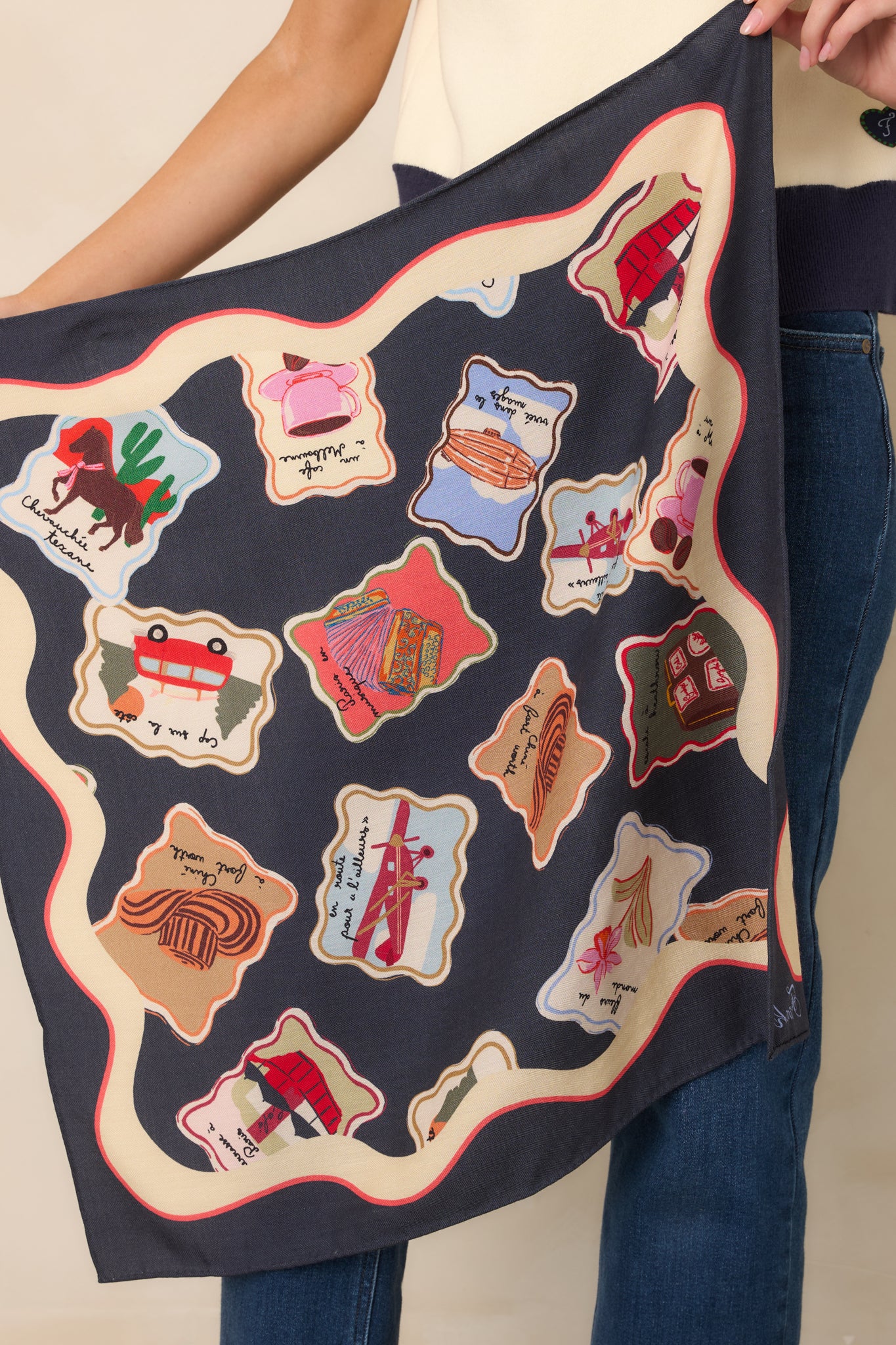 Midnight blue hair scarf featuring colorful illustrated motifs inspired by travel, cafés, books, florals, and everyday moments, framed by a scalloped ivory border with coral-red trim.