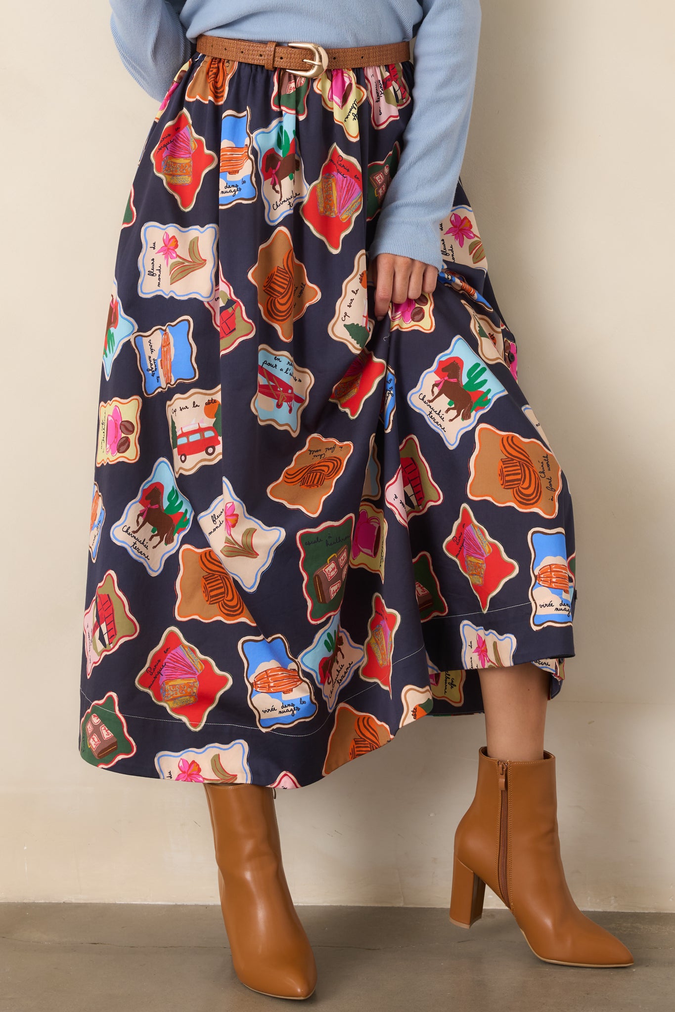 Detailed view of the midnight blue skirt highlighting its colorful illustrated stamps inspired by travel, cafés, books, and florals.