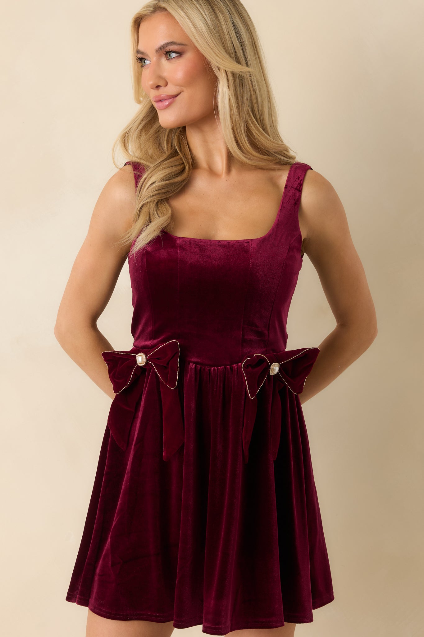 Midsection crop highlighting fitted waist, bow accents with faux pearls, and velvet fabric texture.