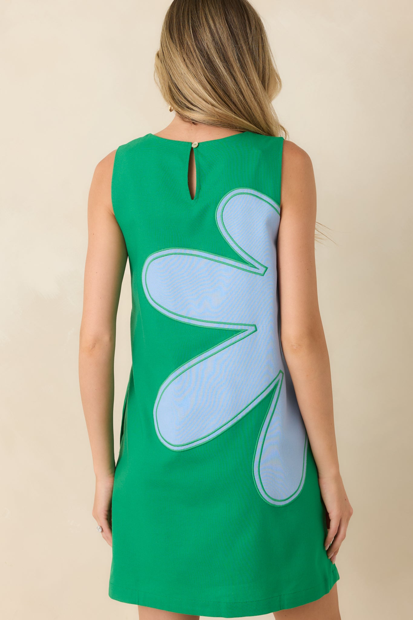 Back view of the sleeveless mini dress featuring a relaxed silhouette and keyhole button closure.