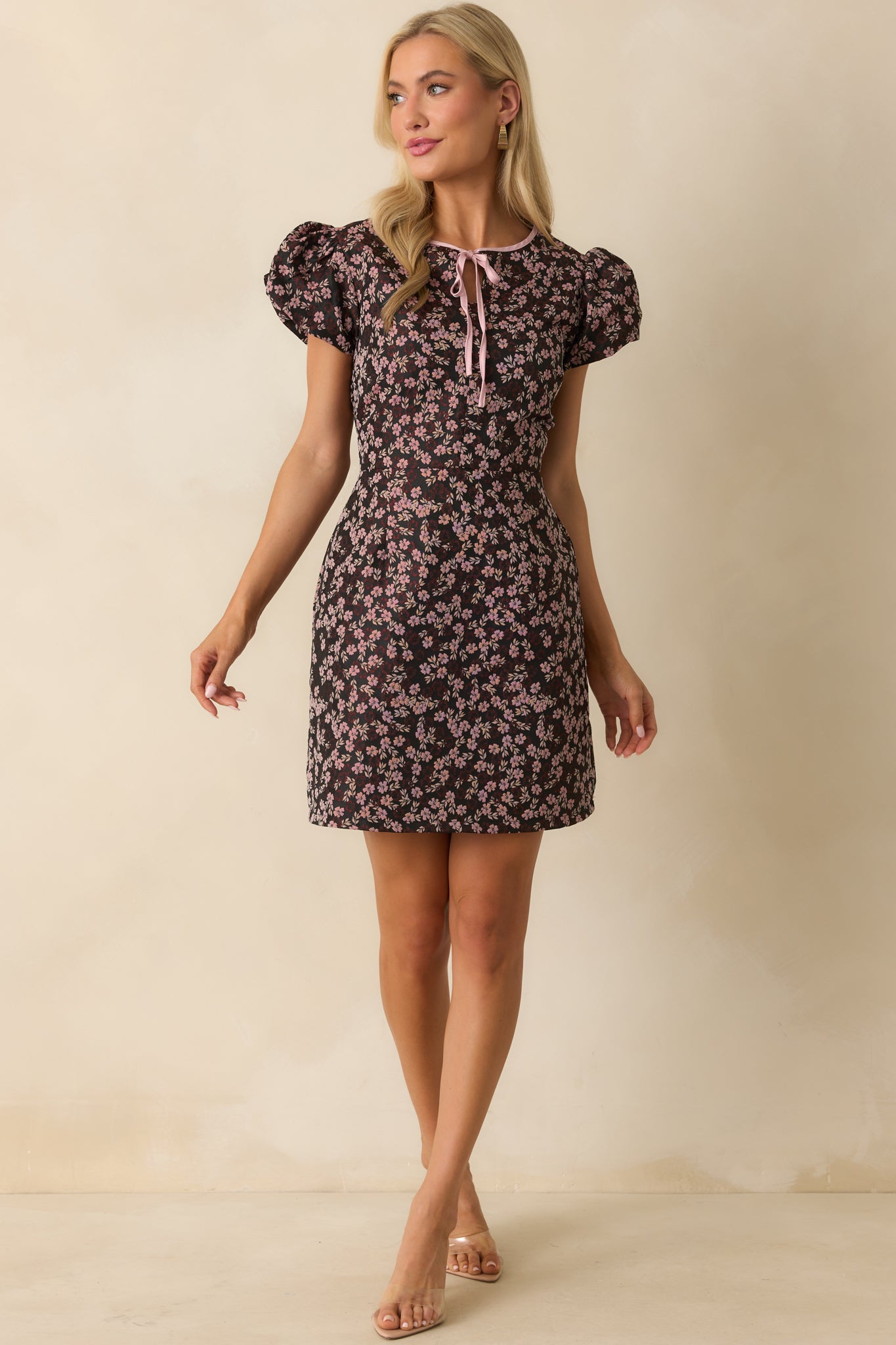 Mini dress with black base, pink floral pattern, and tailored silhouette.