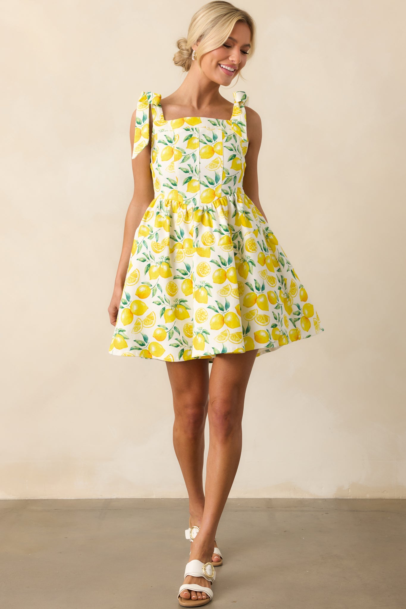 Mini dress displayed in a full view, highlighting the playful lemon pattern and structured drop waist design.
