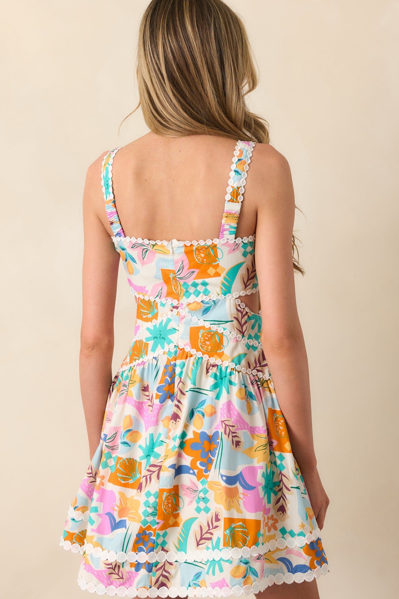 Rear view of the mini dress revealing the hidden zipper closure and continuous patterned fabric across the back with thin elastic straps.