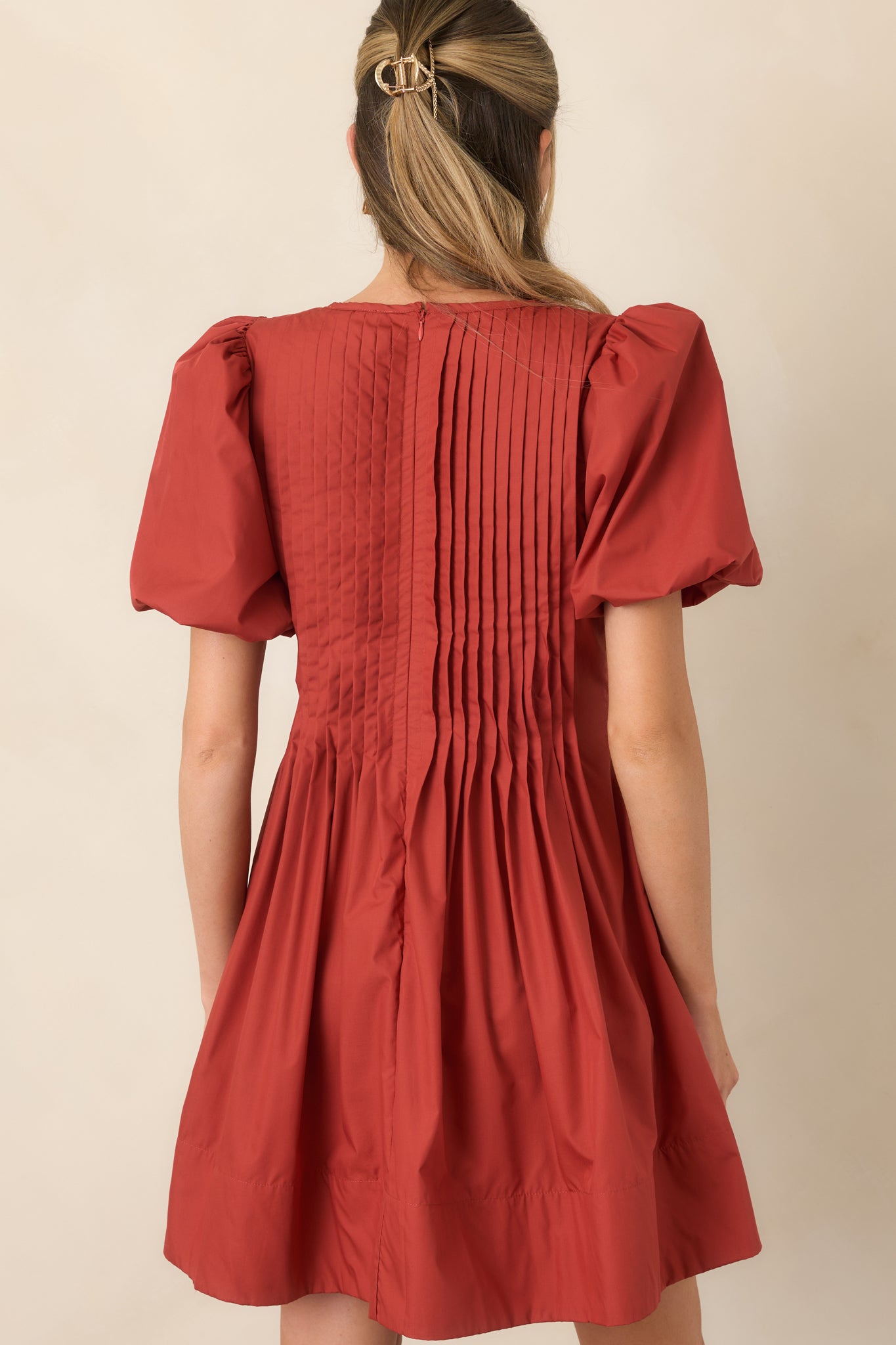 Rear view of the mini dress showcasing pintucking across the bodice, puff sleeves, gathered skirt, and concealed zipper.