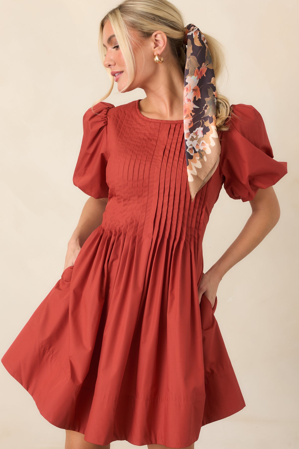 Side pockets complement the dress’s full gathered skirt and structured pintucked bodice with voluminous puff sleeves.