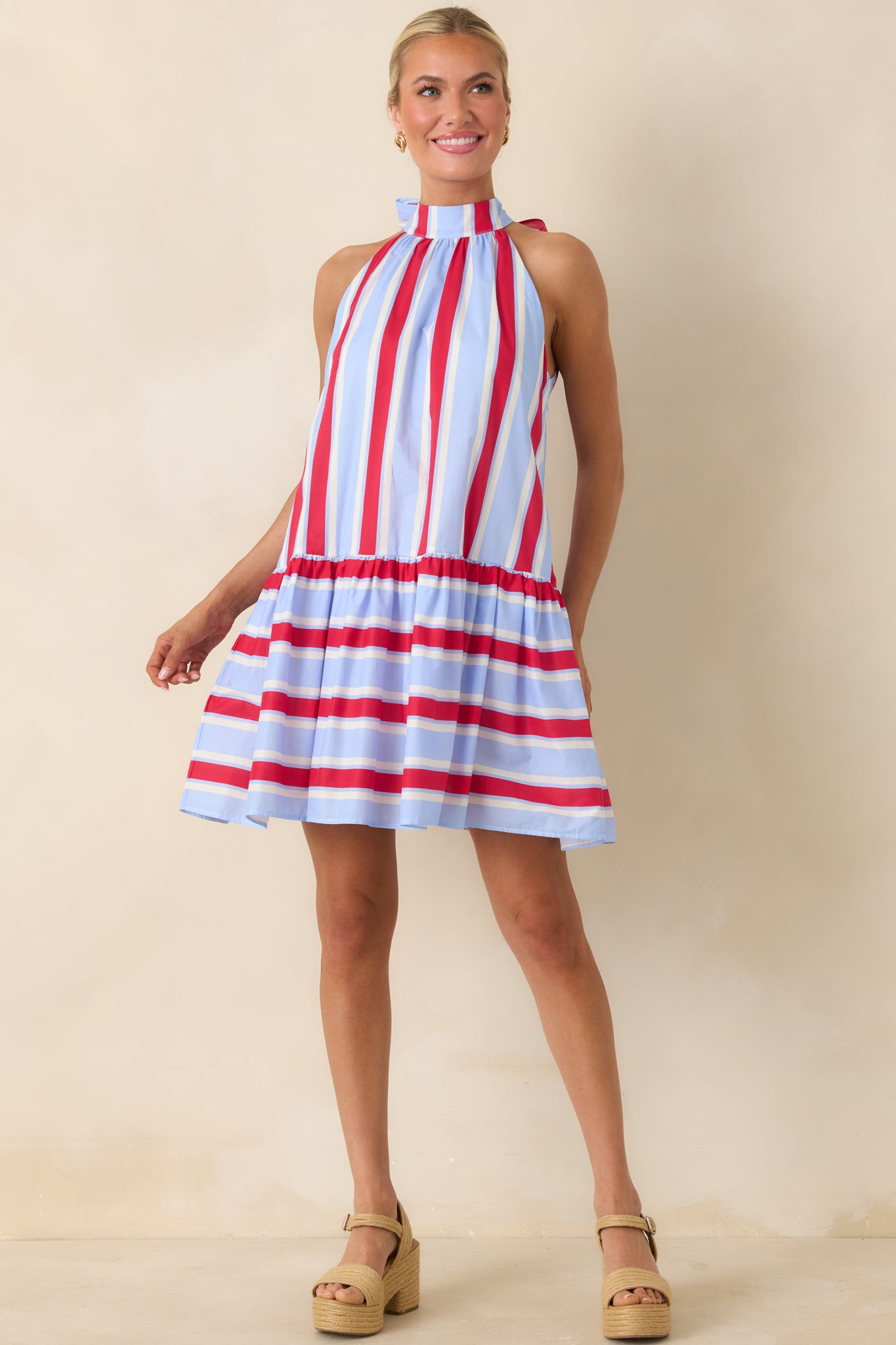 Mini dress with halter neckline, red and soft blue stripes, and tiered gathered skirt.