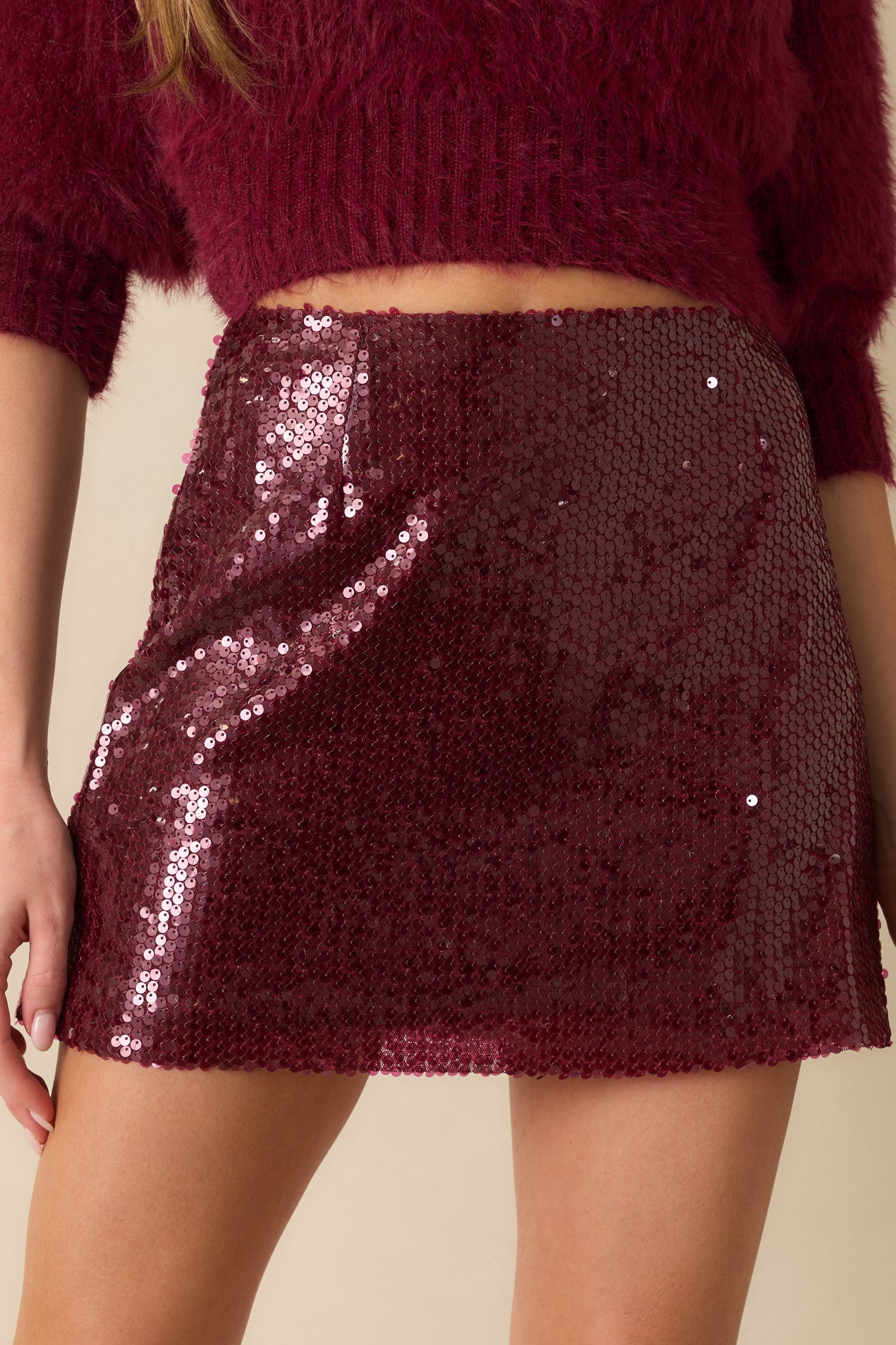 The mini skirt displays its sleek straight silhouette with allover wine purple sequins and smooth polyester lining.