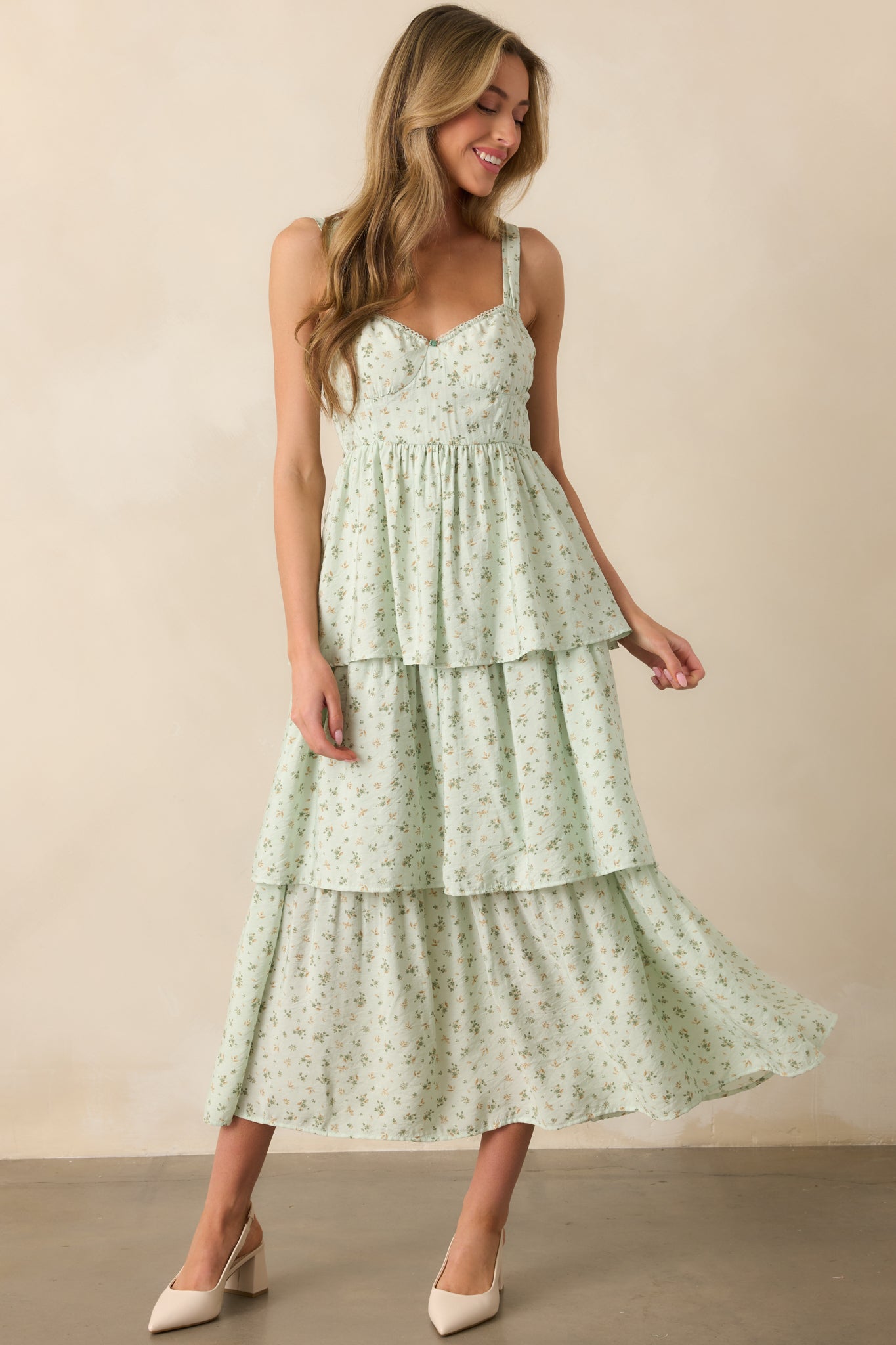The mint floral maxi dress in a front-facing view, emphasizing the elegant tiered skirt, adjustable straps, and bustier-style bodice with stitch detailing. The small center bust flower adds a charming touch