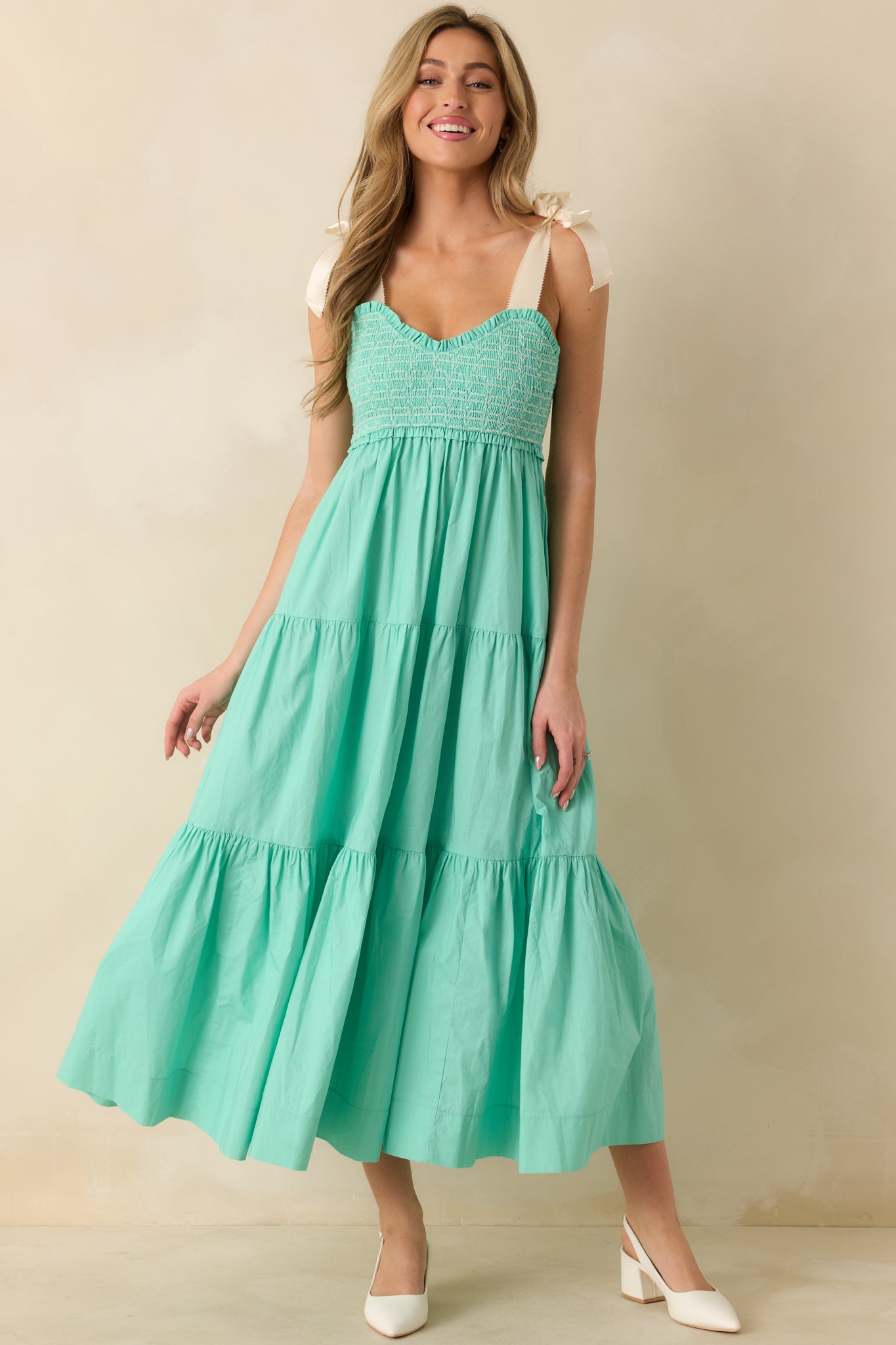 Mint green midi dress with sweetheart neckline, smocked embroidered bust, ivory bow straps, and flowy skirt with pockets.
