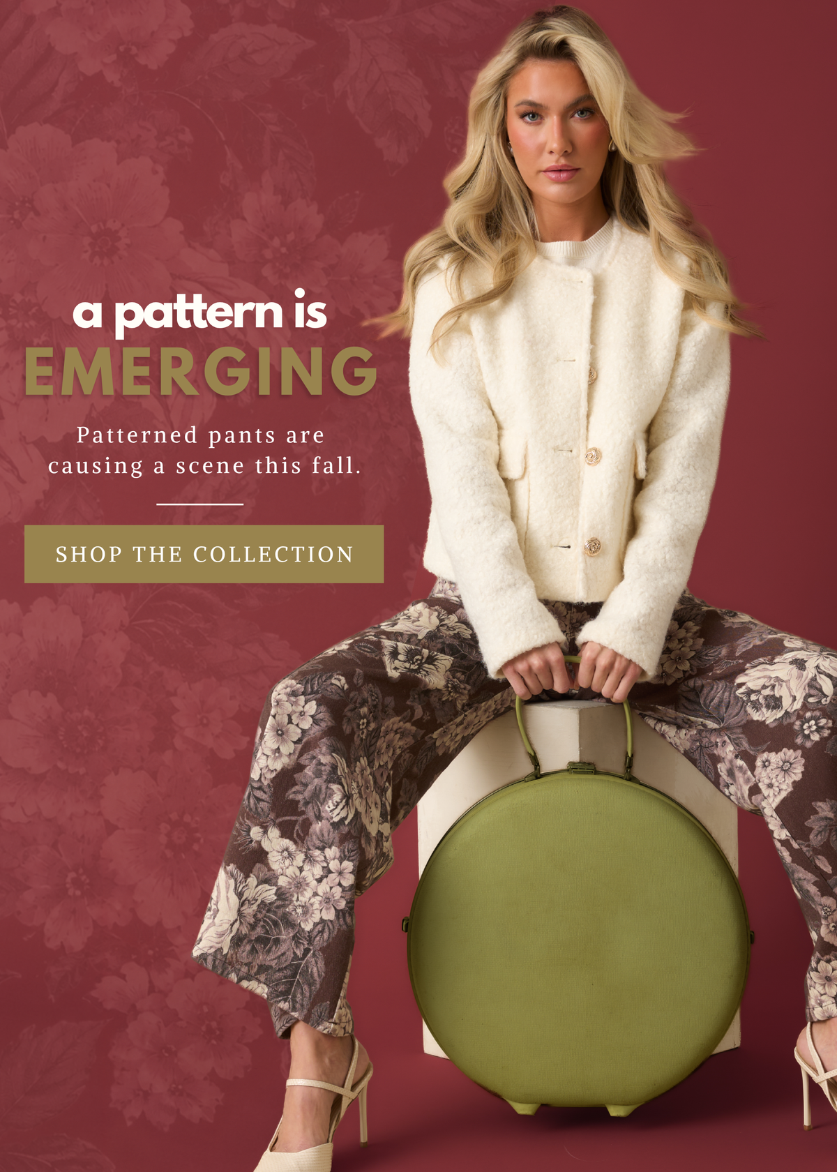 Model wearing a white jacket and floral pants, against a burgundy floral backdrop. Text reads: "A pattern is emerging. Patterned pants are causing a scene this fall. Shop the collection."