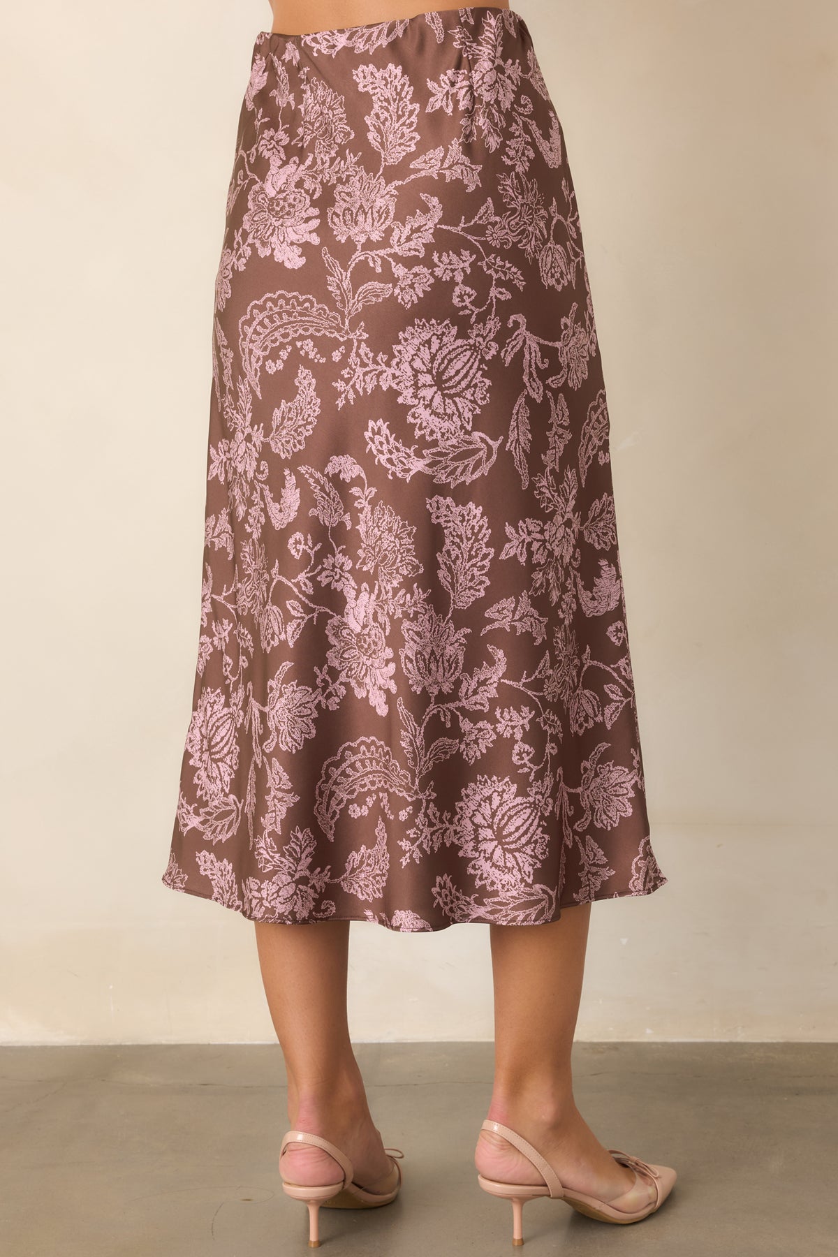 Mocha brown satin midi skirt showcasing the elastic waistband and flowing silhouette from the rear.