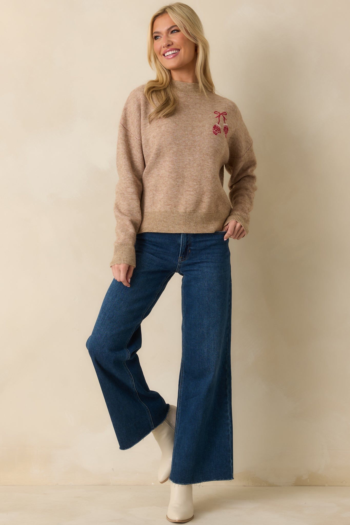 Mocha knit sweater with a relaxed fit, ribbed trim at neckline, cuffs, and hem, and embroidered red mitten accents on the chest.