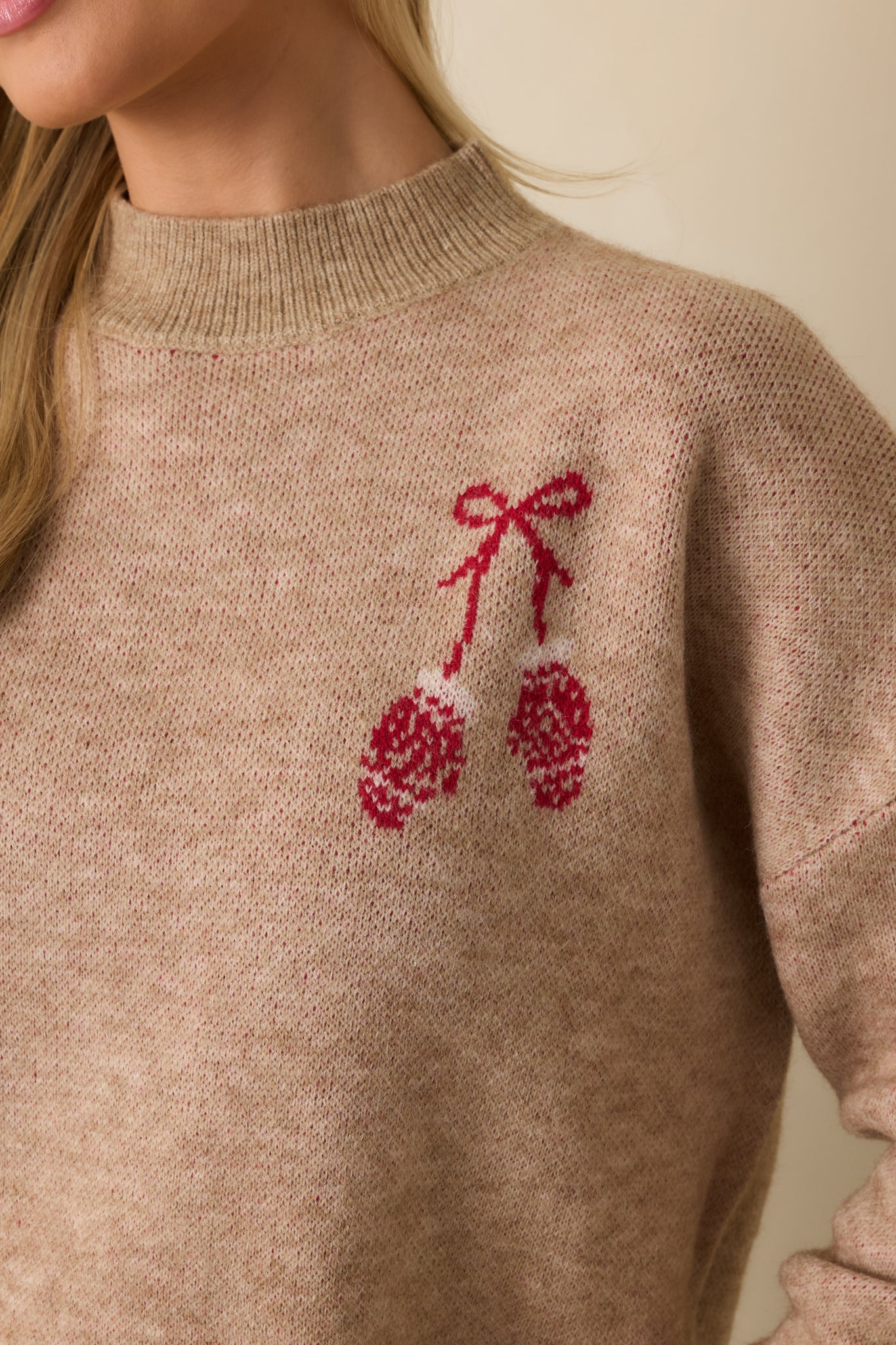 Detailed shot of the mocha sweater’s embroidered red mitten accents, ribbed trim, and soft knit fabric.
