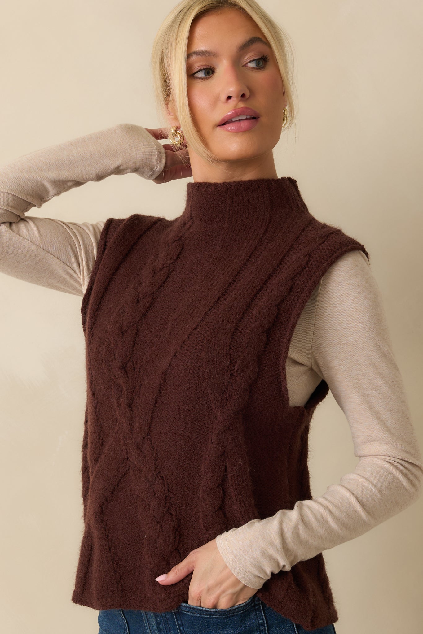 Close view of the mock neckline and detailed cable knit pattern on the front of the vest.