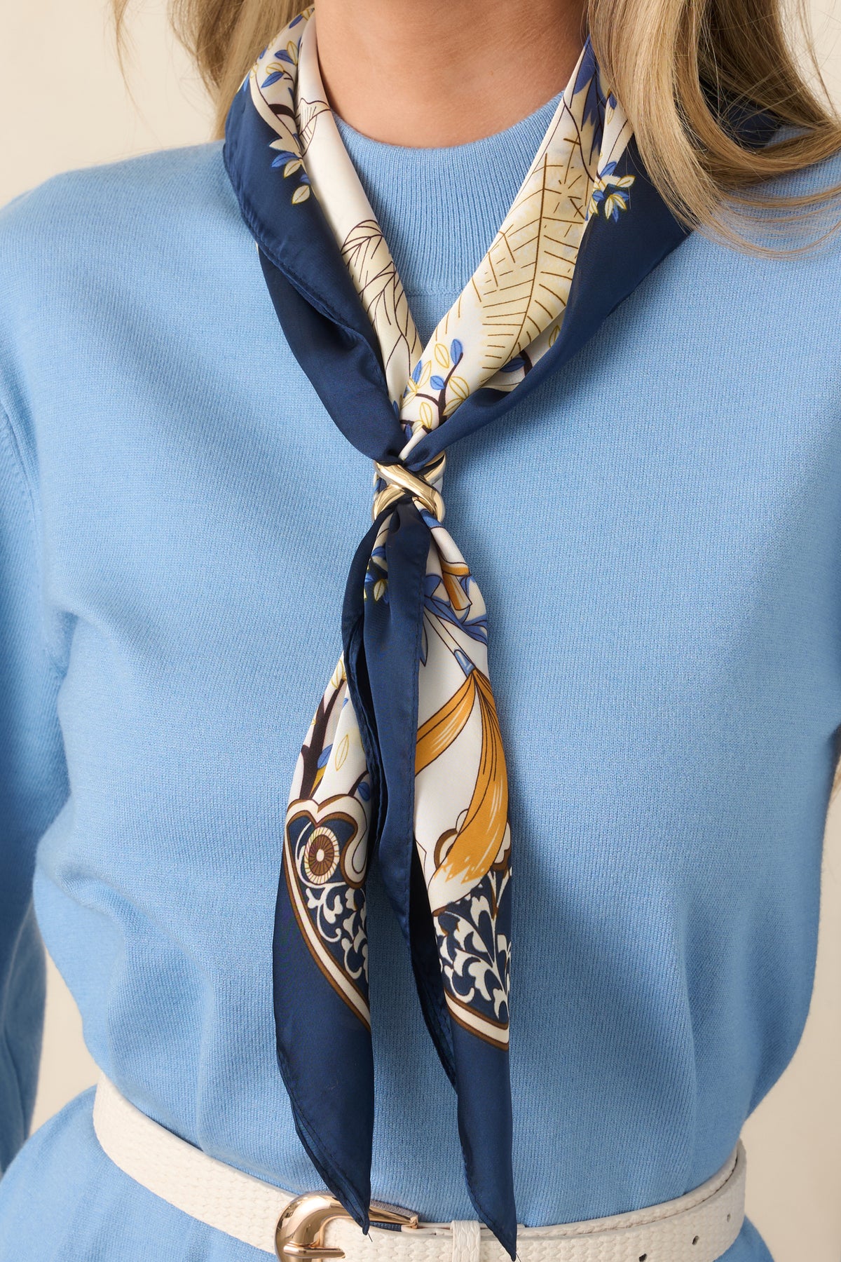 Modern gold-tone scarf ring showcasing its sleek open shape and refined metallic finish.