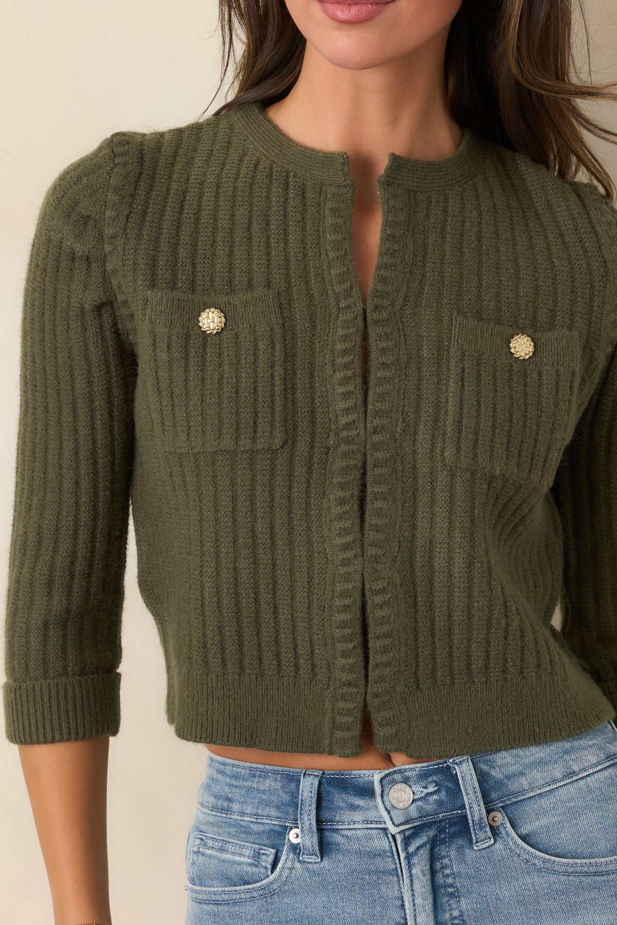 Close view of the vertical ribbing, gold-tone buttons, chest pocket, and ribbed neckline edging.