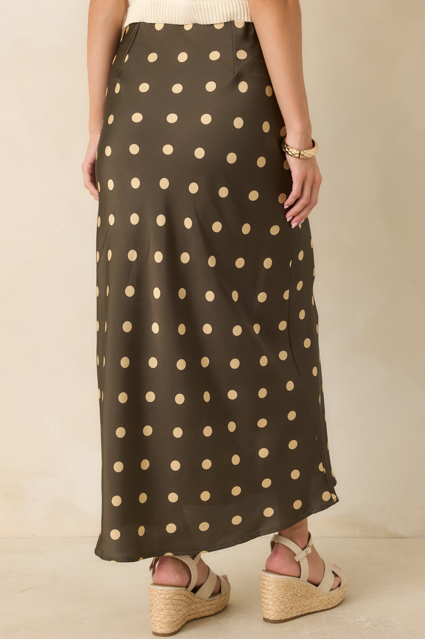 Rear view of the moss green satin skirt featuring a flowing bias-cut silhouette and elastic waistband.