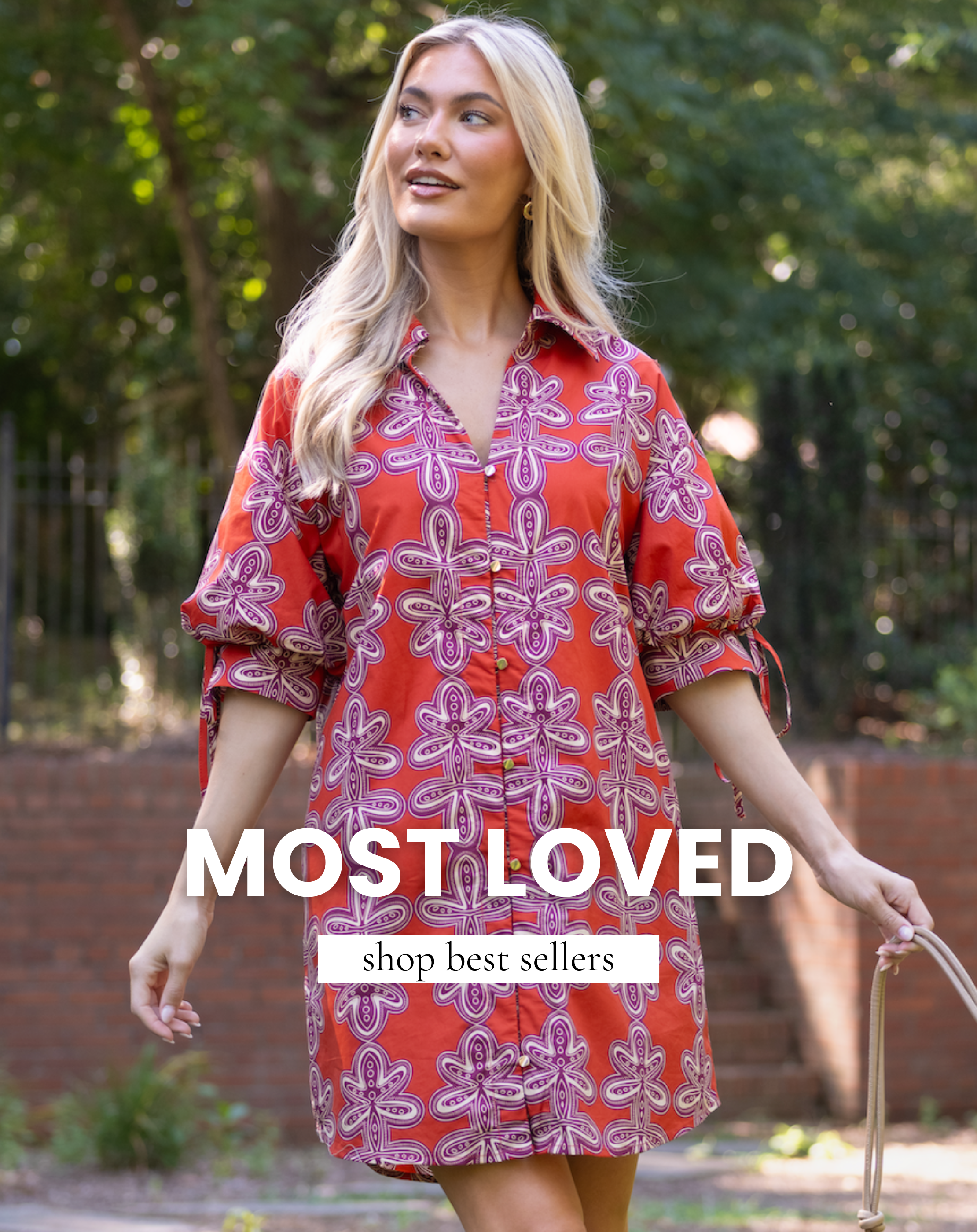 Model wearing a red and pink printed shirt dress while walking outdoors. Text reads: "Most Loved. Shop Best Sellers."