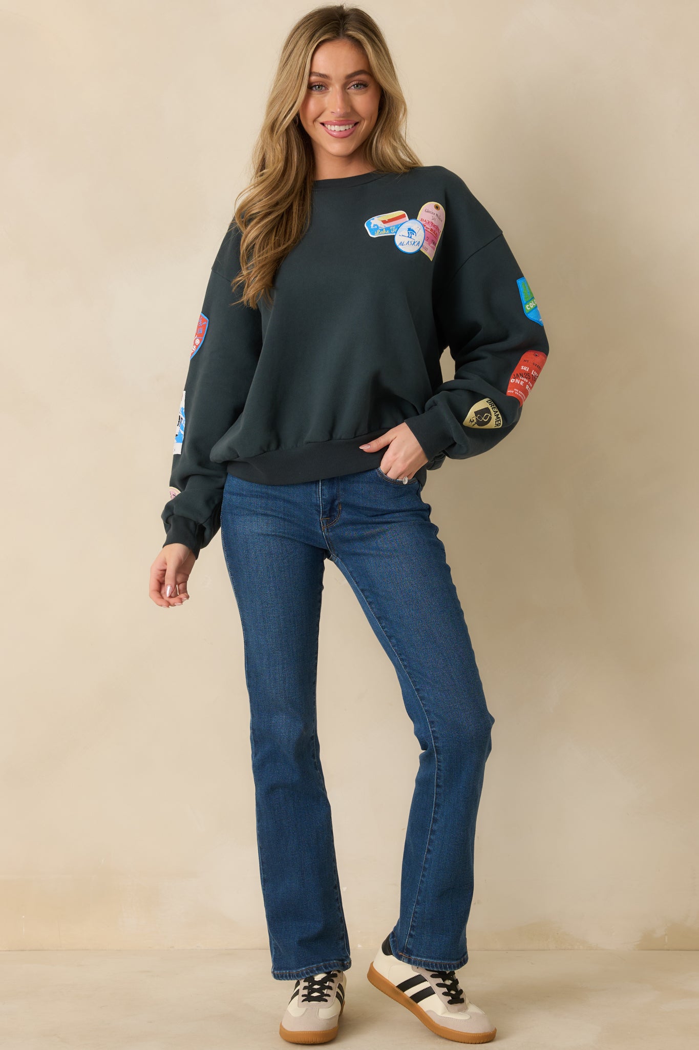 Multi-colored ski patches displayed across the front of the vintage black sweatshirt.