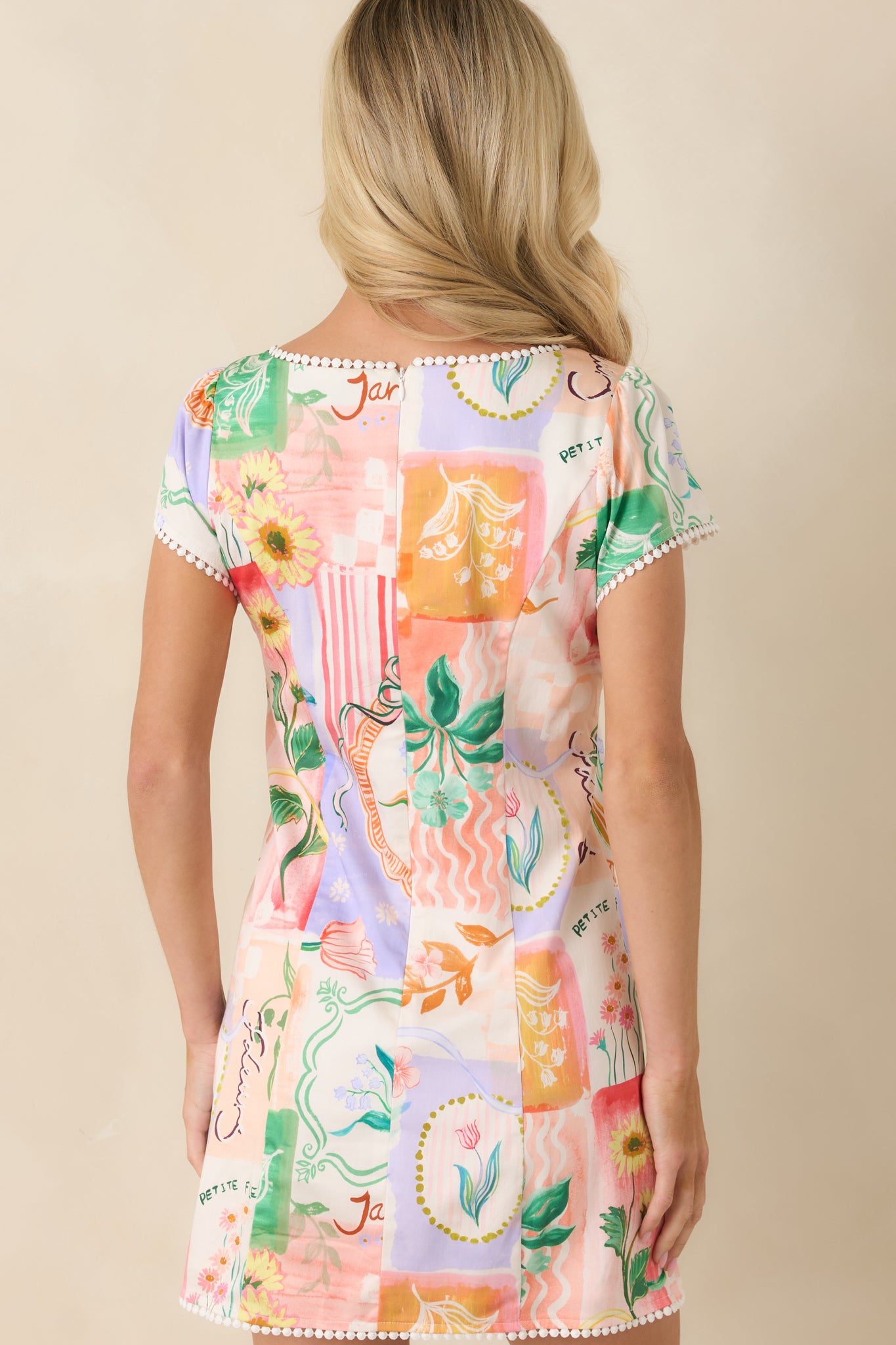 Back view of the multi floral print mini dress featuring the A-line silhouette, colorful patchwork-inspired pattern, and concealed zipper closure.
