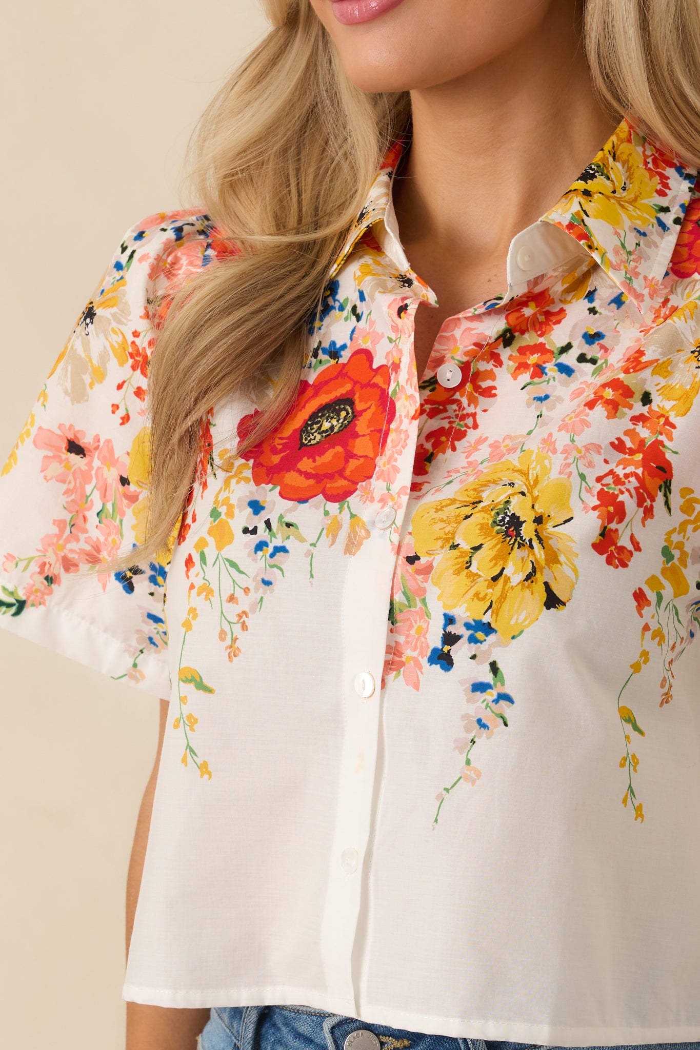 Detailed view of the multicolor floral print and smooth cotton texture on the white button-down top.