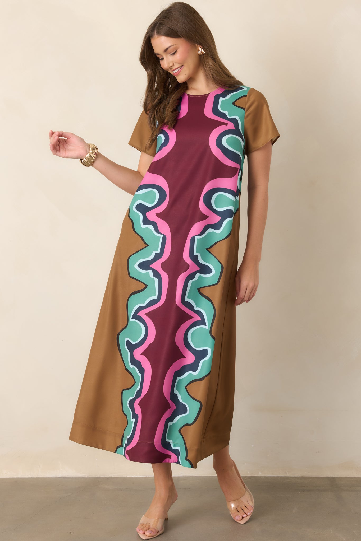 Multicolored serpentine maxi dress showcasing its flowing length, short sleeves, round neckline, and bold combination of burgundy, camel, blue, green, and pink hues.