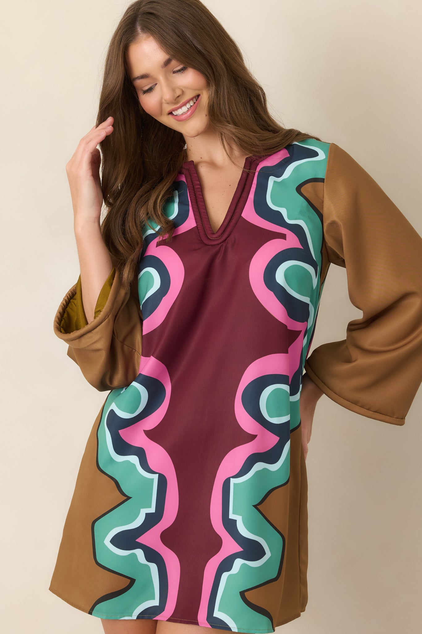 Detailed view of the vibrant dress showcasing the burgundy, camel, seafoam green, pink, navy, and light blue abstract pattern.