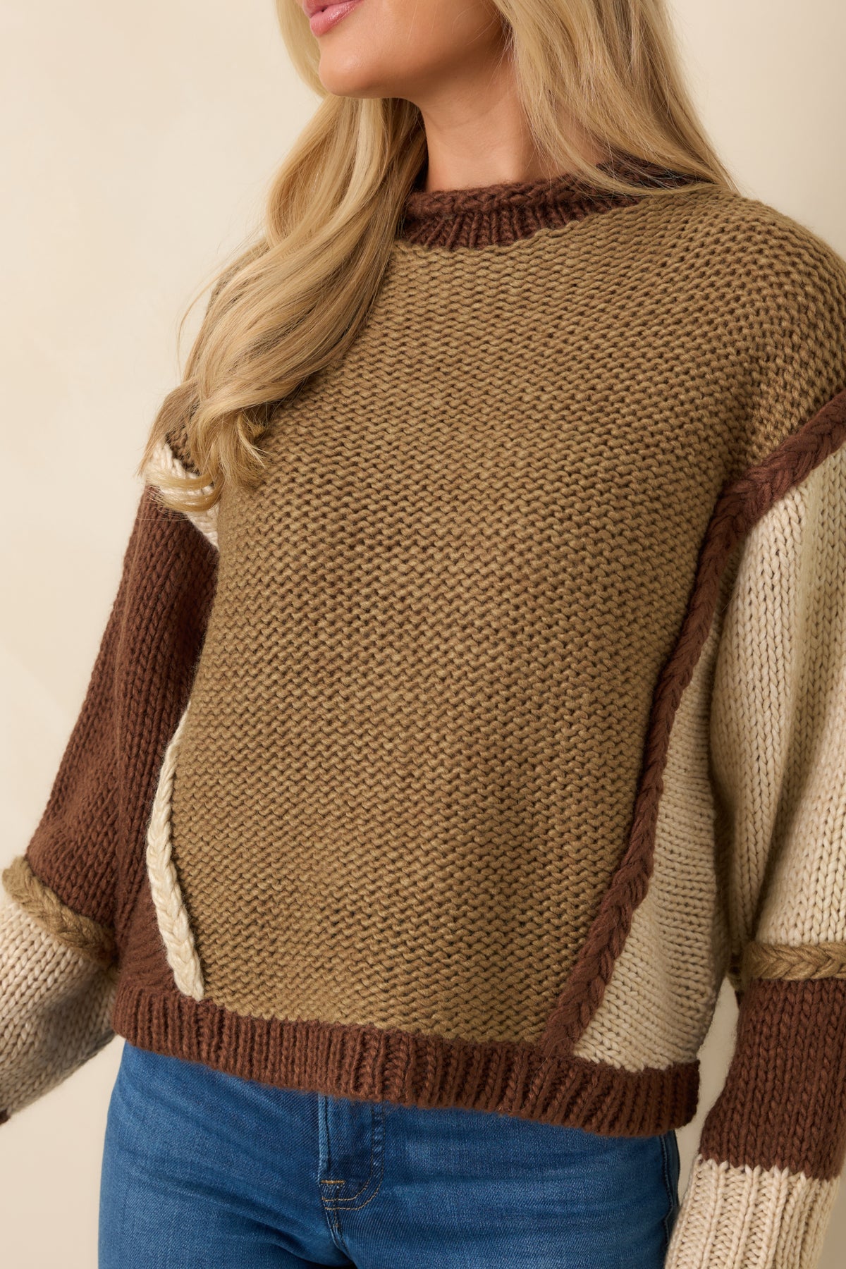 Raised braided knit seams and contrasting yarn textures create dimension across the multicolored sweater.