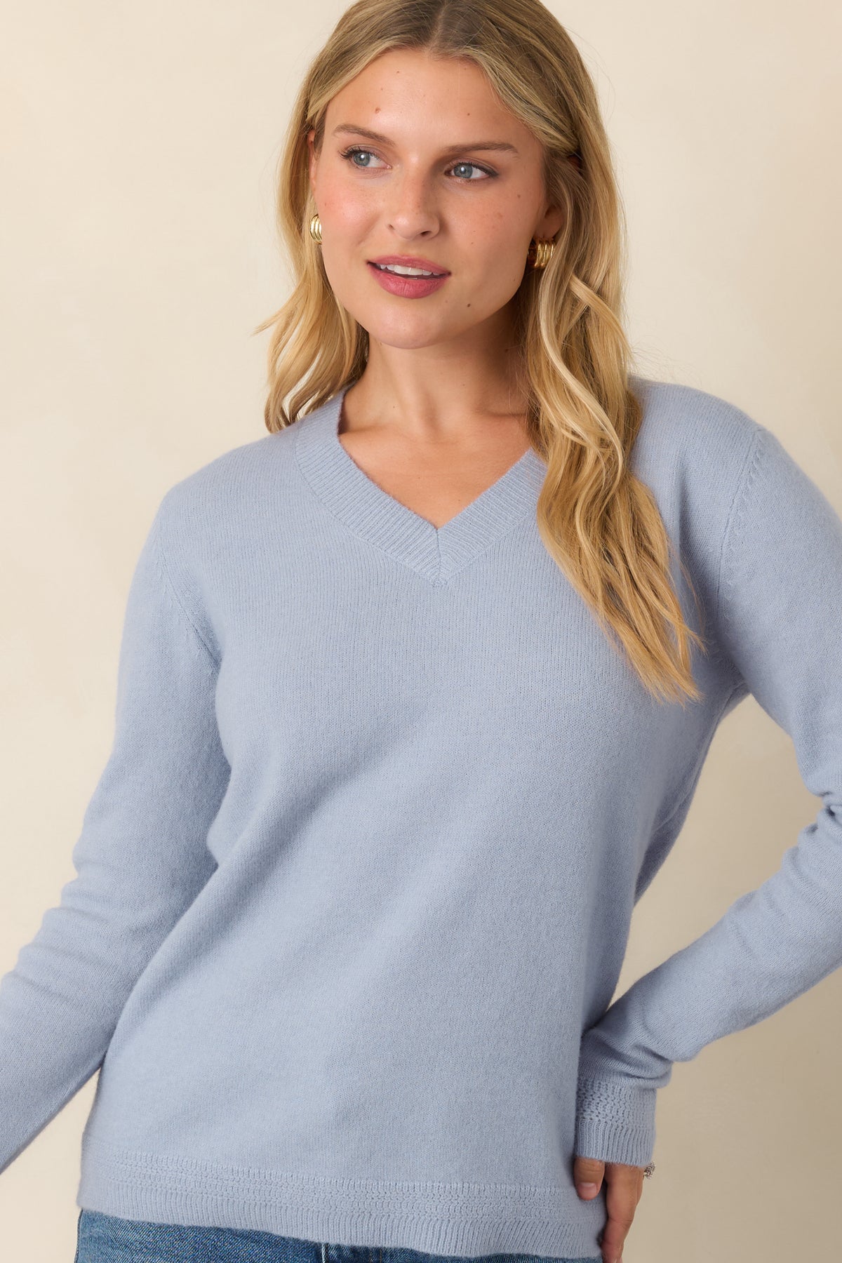Muted dusty blue top showcasing the clean V-shaped neckline, gently relaxed knit silhouette, and softly defined ribbed edges.