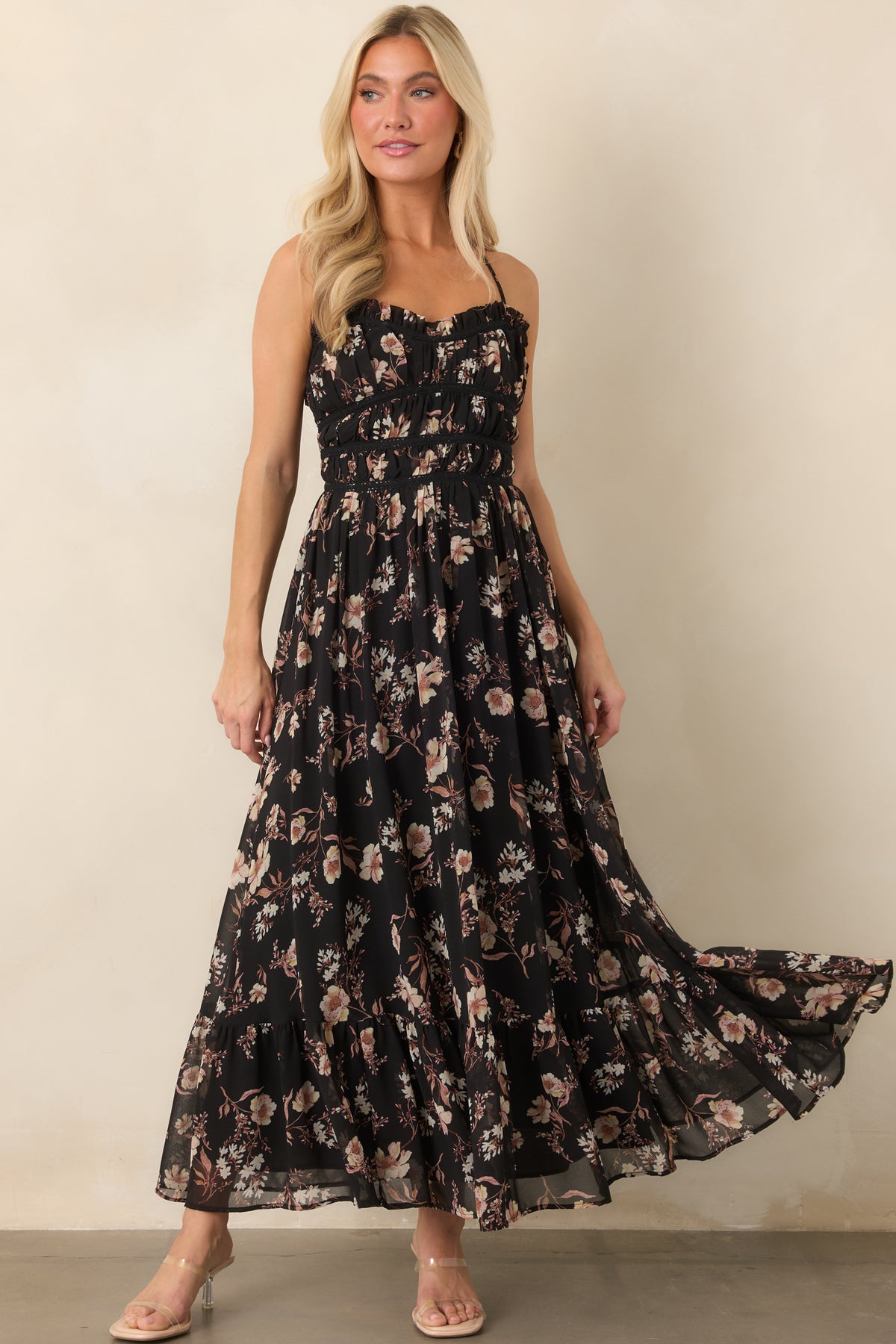 Muted floral blooms decorate the sheer black overlay of this flowing dress with delicate bodice trim and ruffled detailing