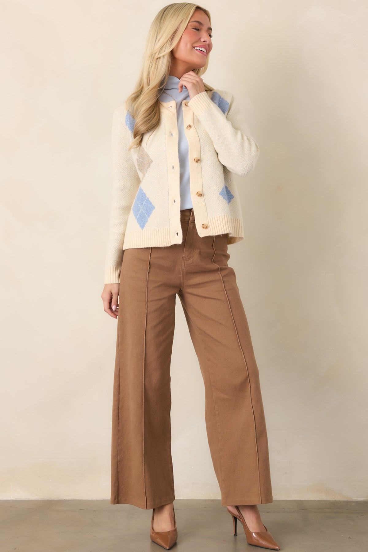 Natural-toned knit cardigan with an intricate argyle pattern, full-length sleeves, ribbed edges, and functional front buttons.