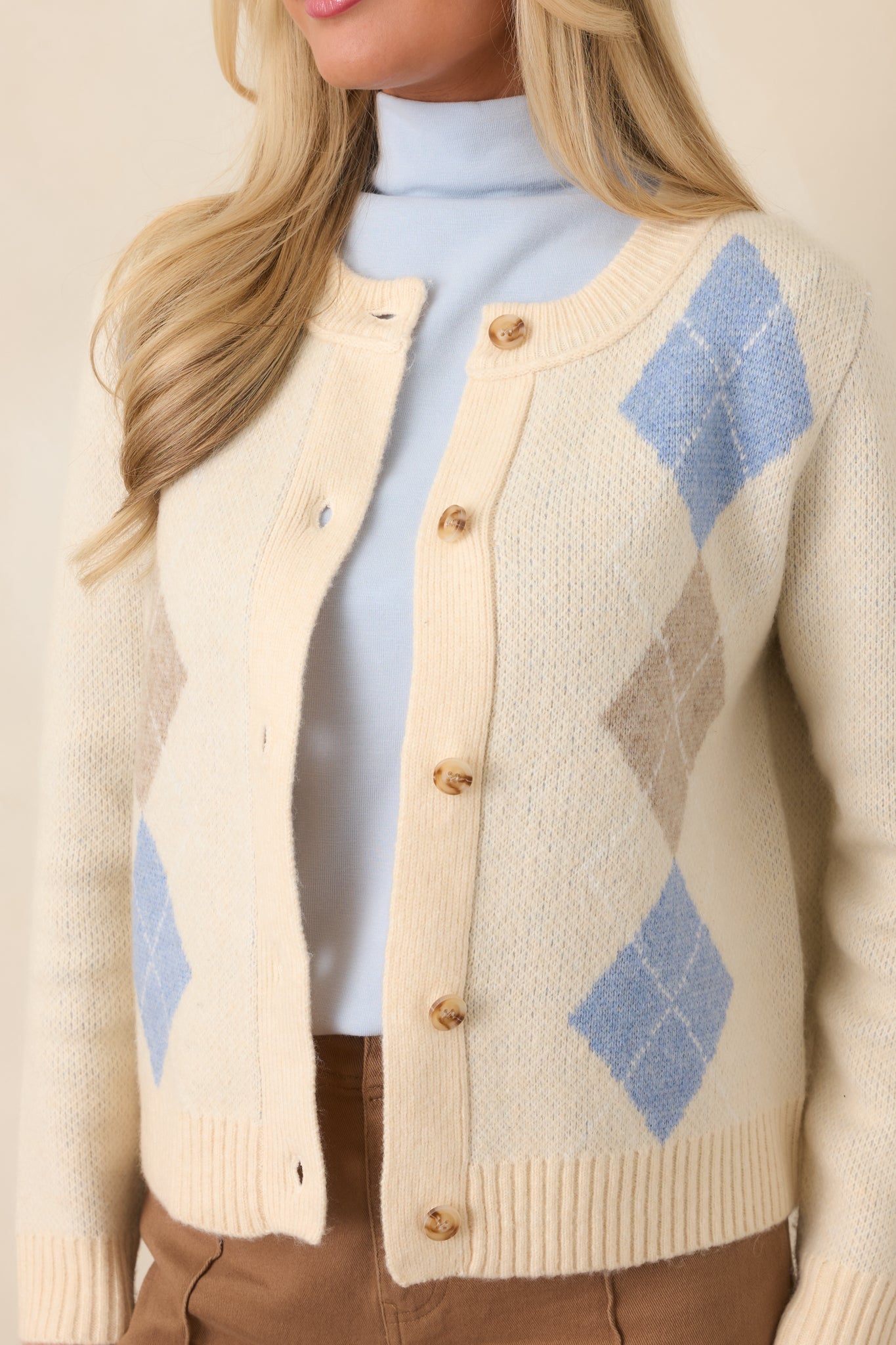 Close-up of the natural multi cardigan revealing the intricate argyle knit pattern with soft blue and warm taupe accents.

