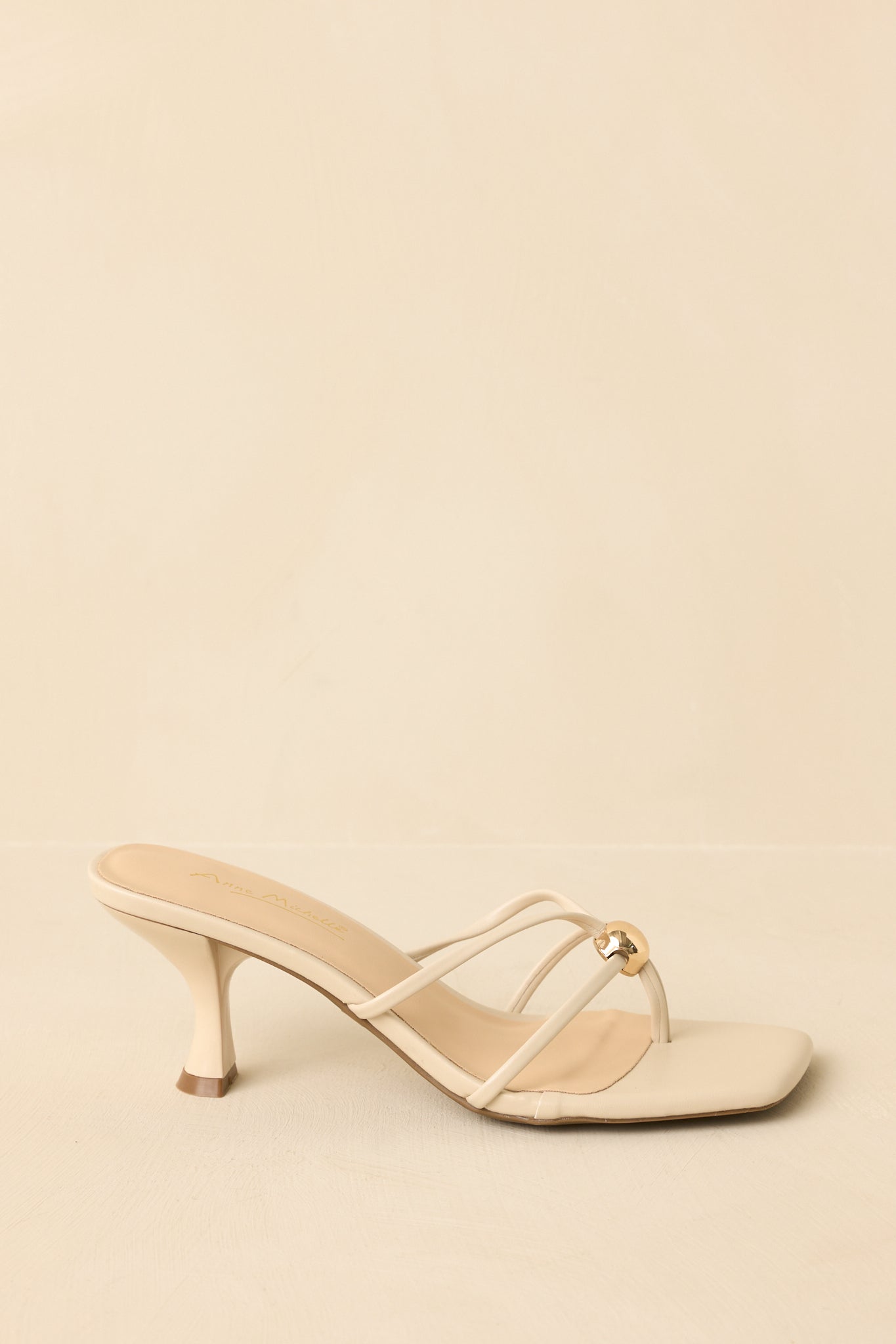Natural strappy sandals displayed from the side to show the full low heel and sleek straps.