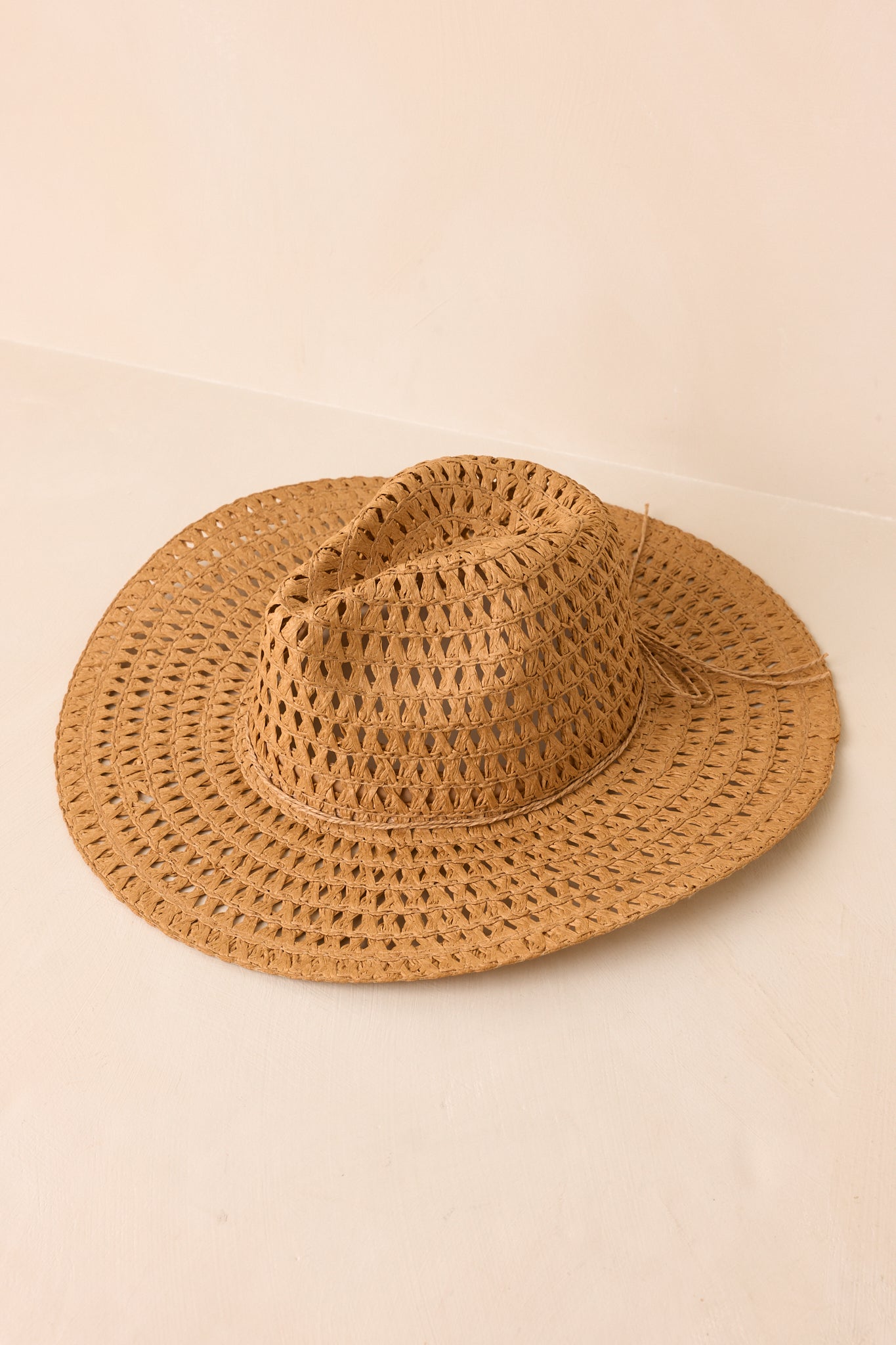 Natural straw cowboy hat displayed from an angled view featuring an open-weave design and wide brim.