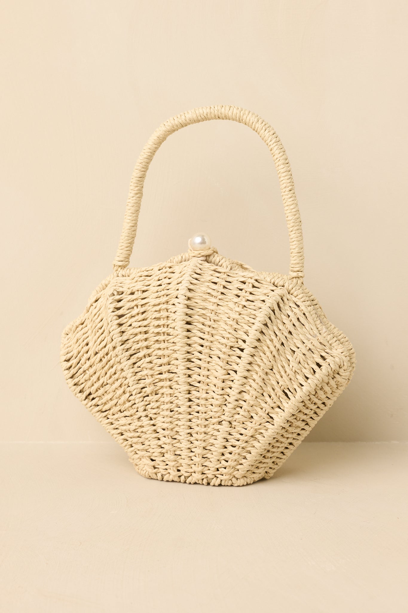 Full view of natural woven shell handbag featuring structured basket weave silhouette and top handle design.