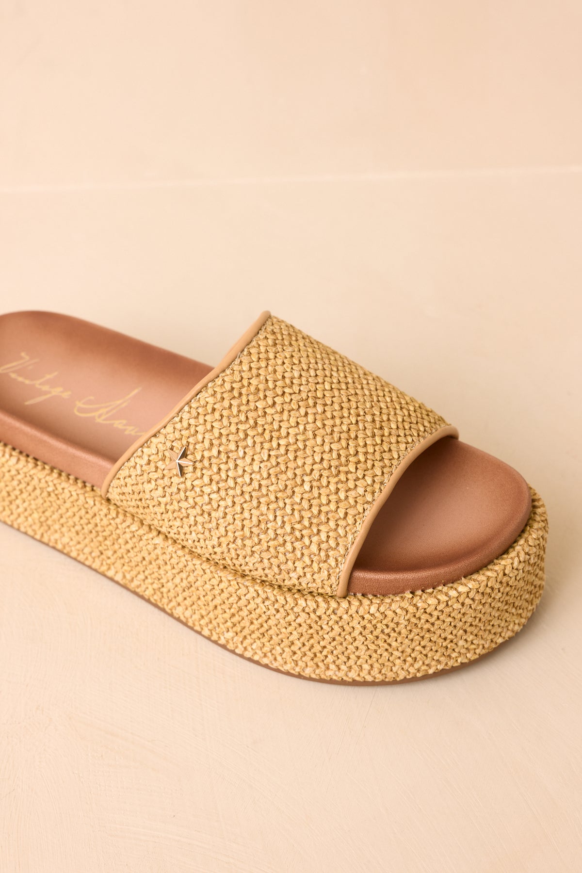 Natural woven platform sandals with wide straps, tan trim, and open-toe styling.
