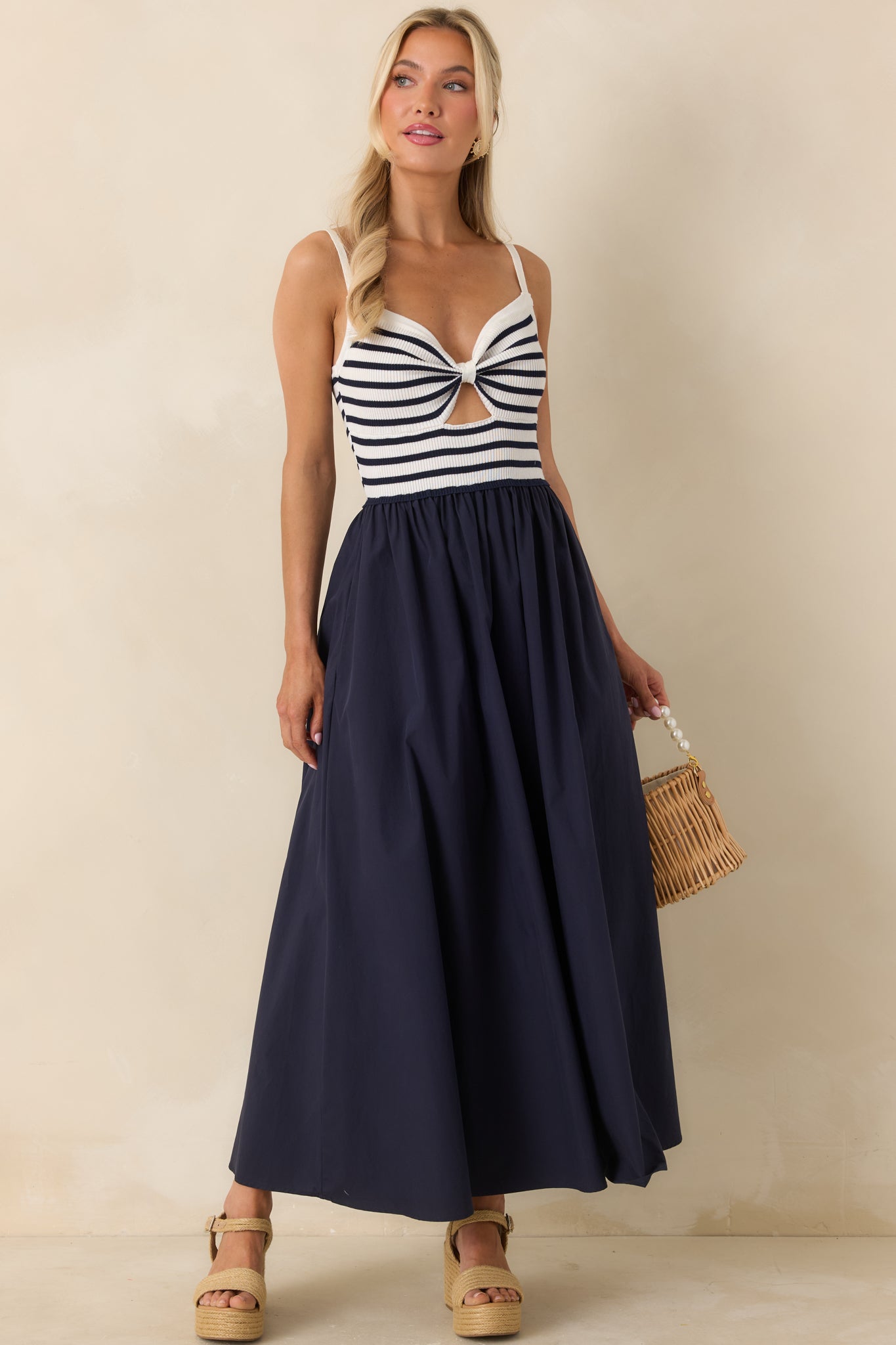 Navy and ivory midi dress with twist-front bodice, subtle cutout, and flowing gathered skirt.