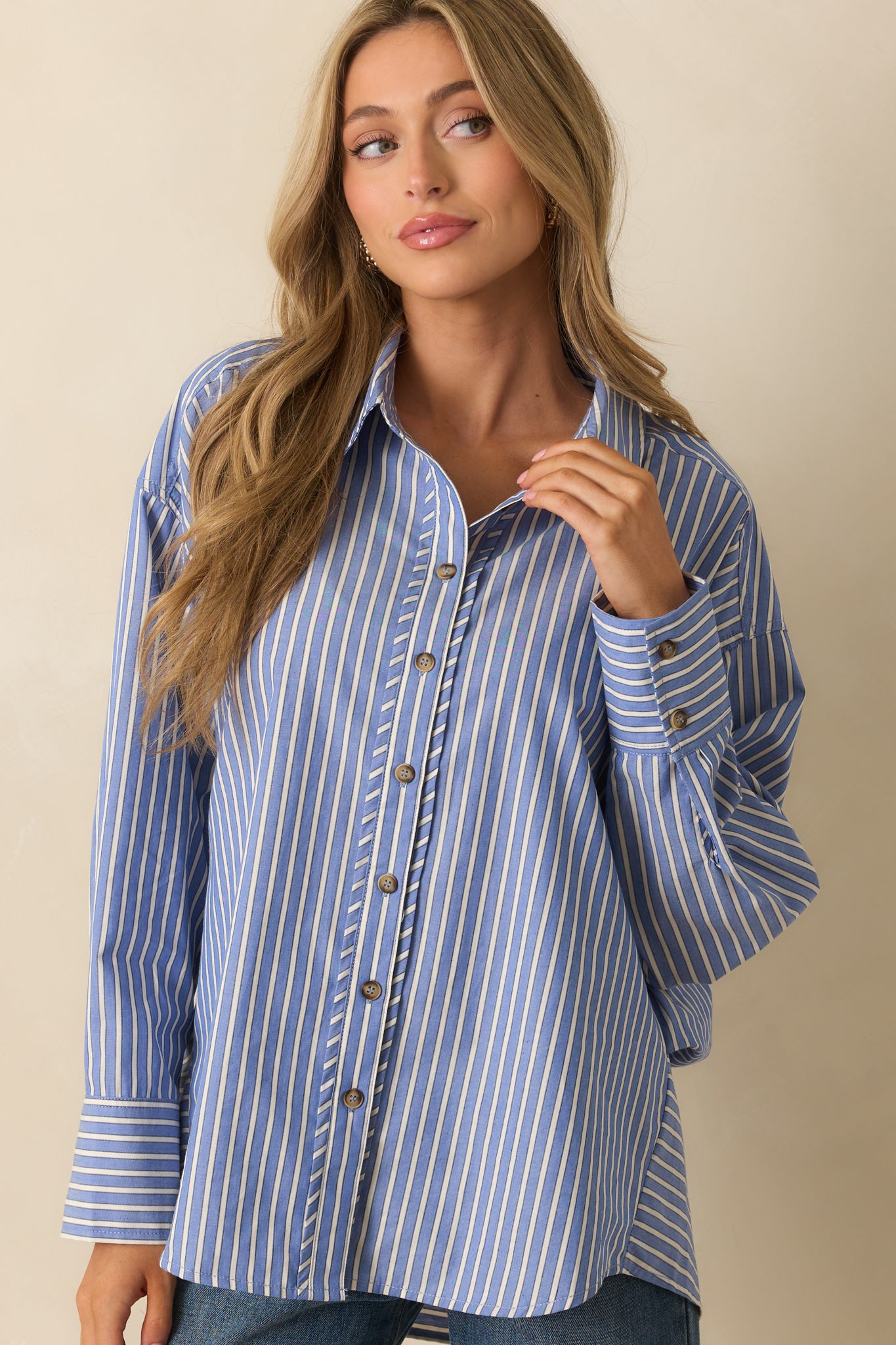 Navy shirt with ivory stripes, collared neckline, long sleeves, and relaxed fit falling over the torso.