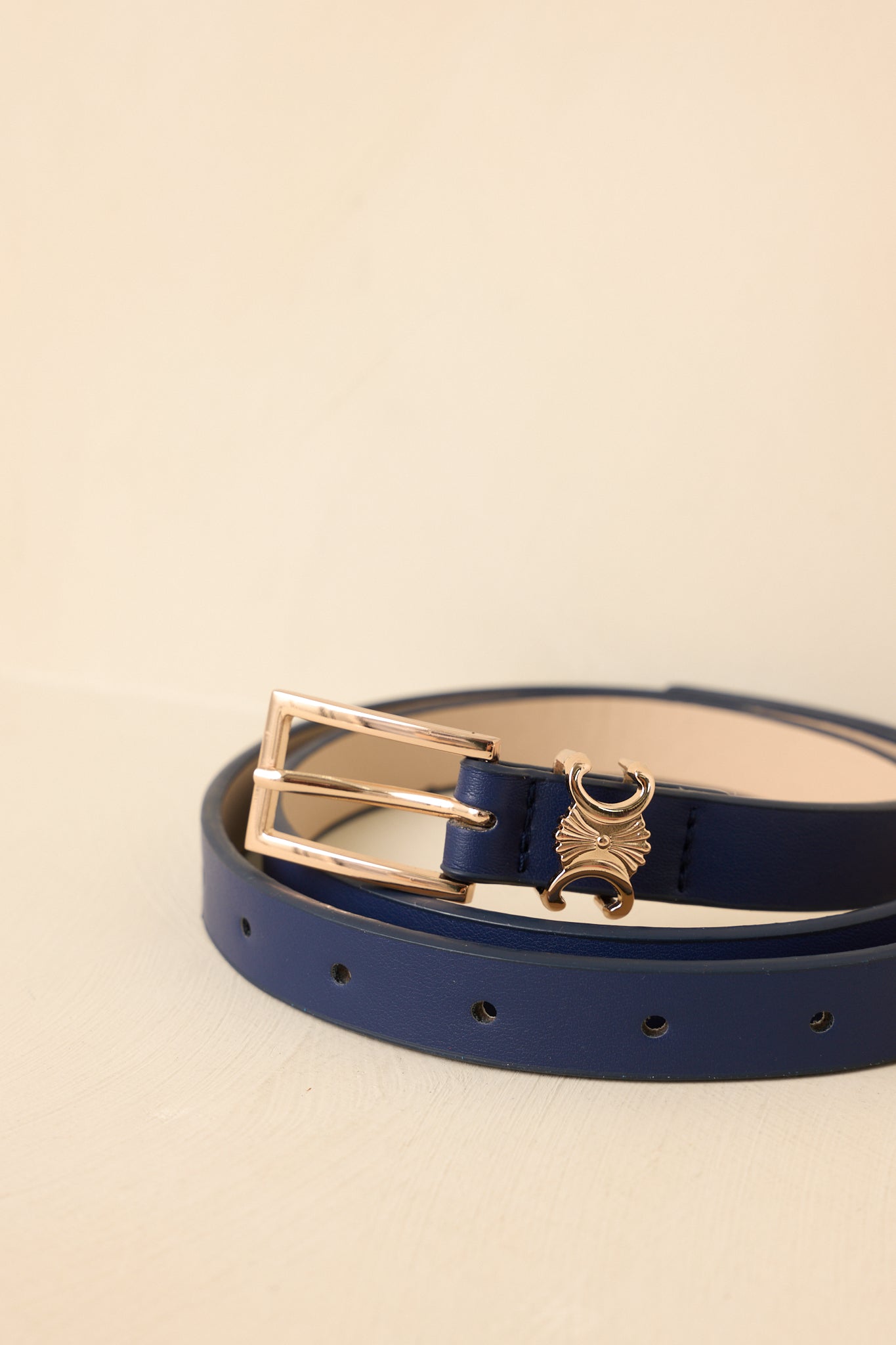 Detailed close-up of navy belt showcasing polished gold-tone buckle and refined faux leather texture.