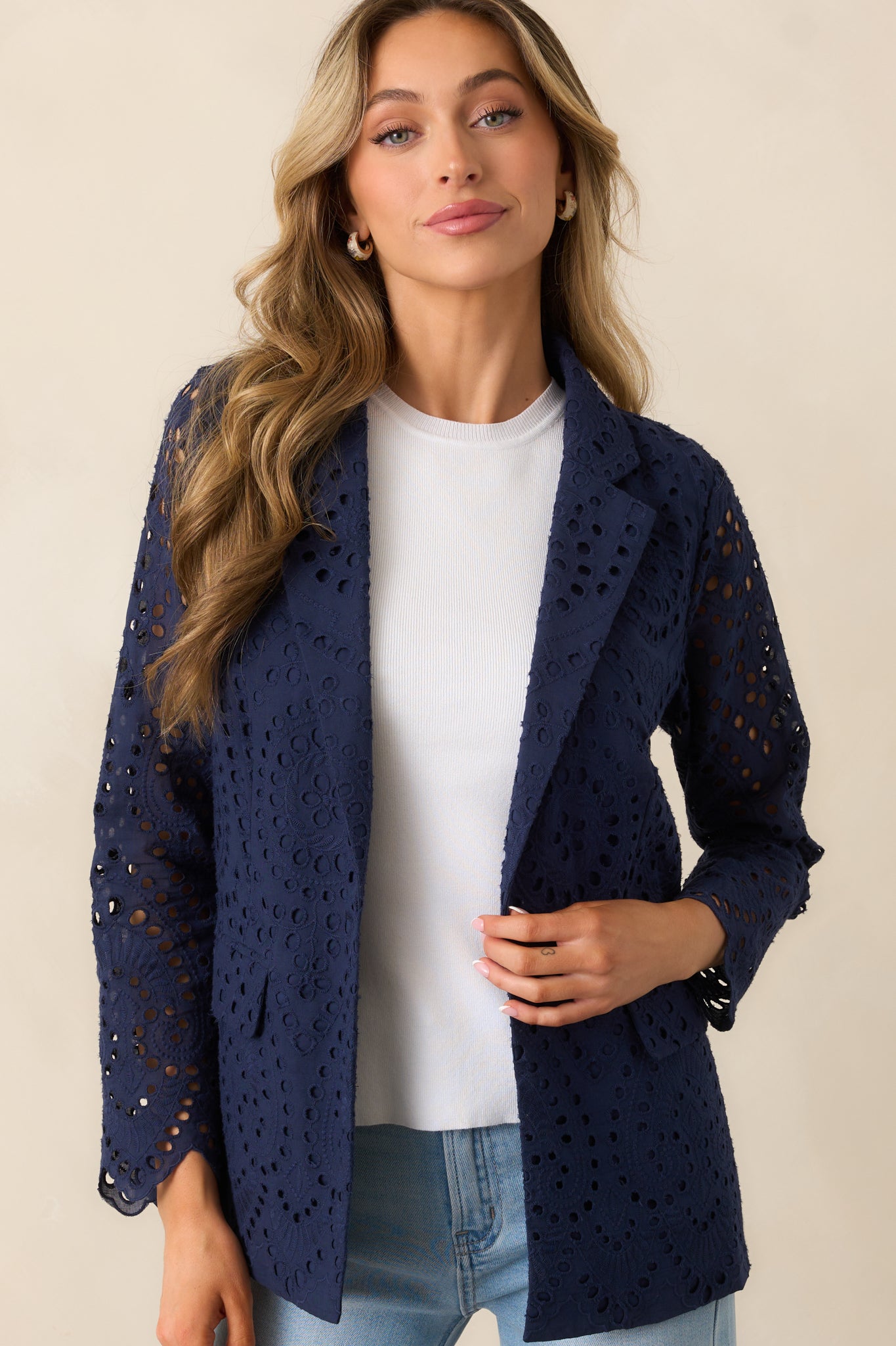 This navy blazer highlights delicate embroidered detailing, paired with a sleek button closure for a timeless look.