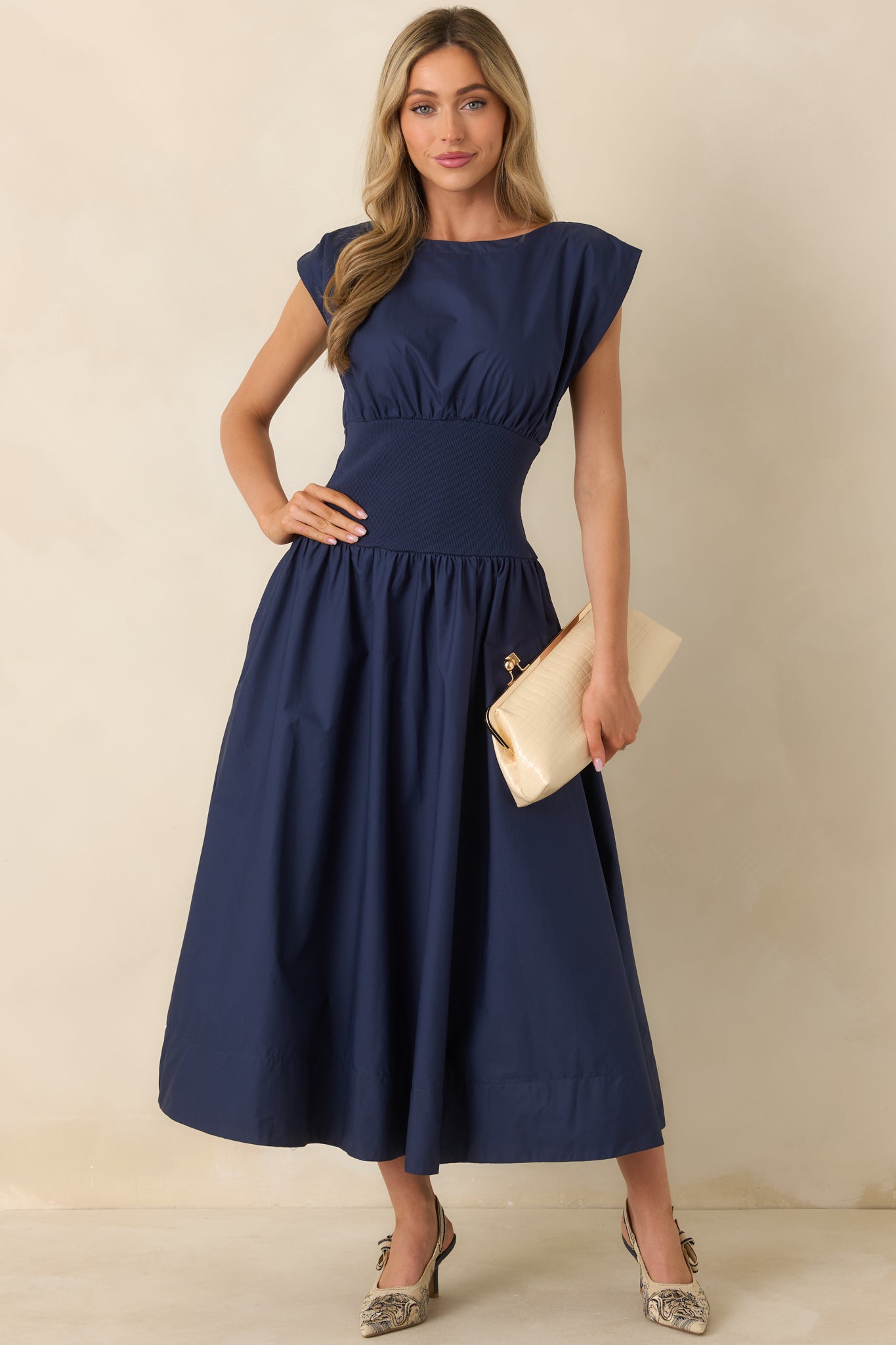 Navy blue midi dress with structured woven fabric, wide boat neckline, cap-style sleeves, and full midi skirt.