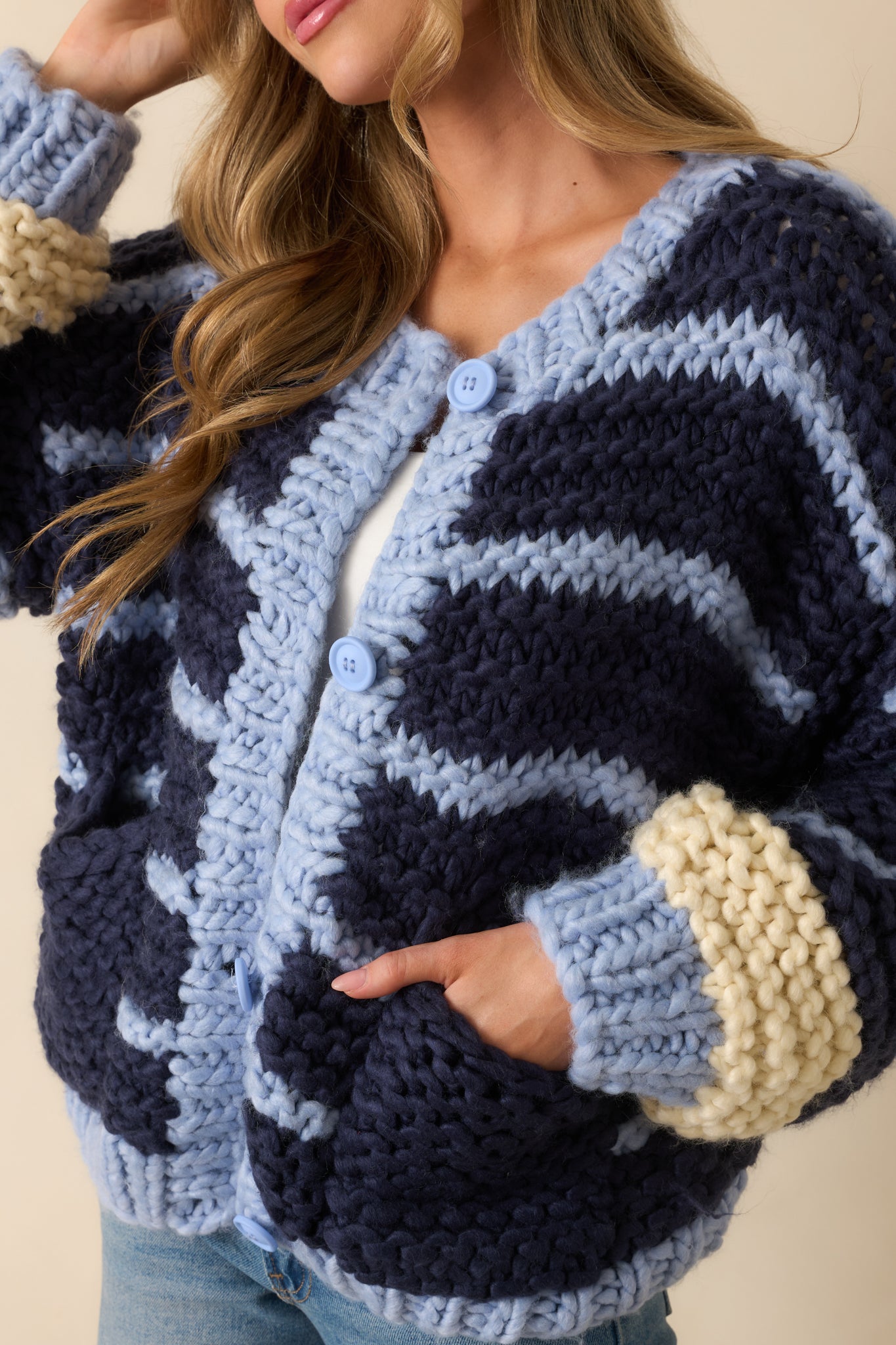 Zoomed-in view of the navy cardigan showing the powder blue and ivory stripe accents, ribbed trim, and button detailing