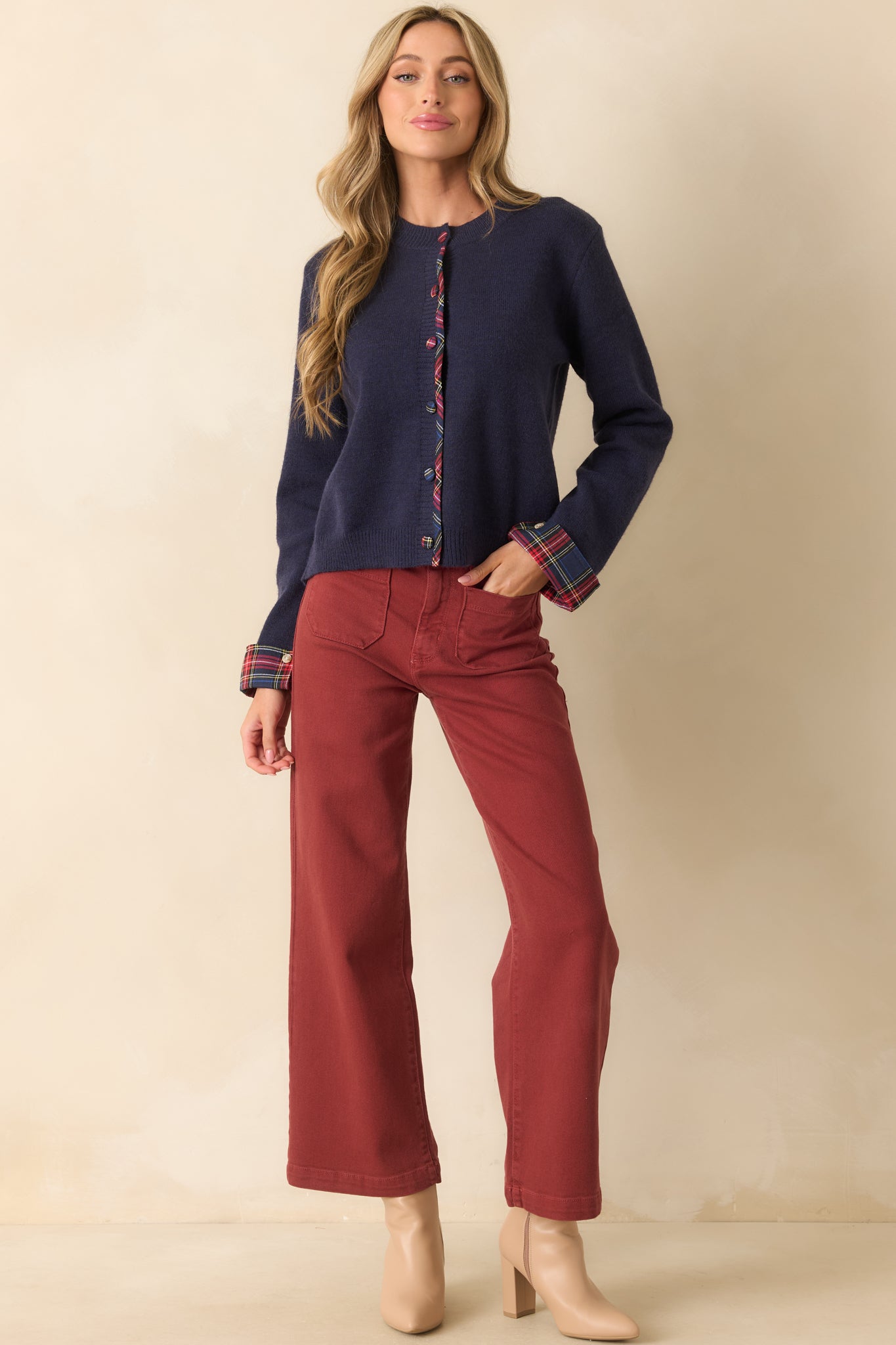 Long-sleeve navy cardigan featuring fold-back plaid cuffs, covered plaid buttons, and a relaxed knit silhouette.