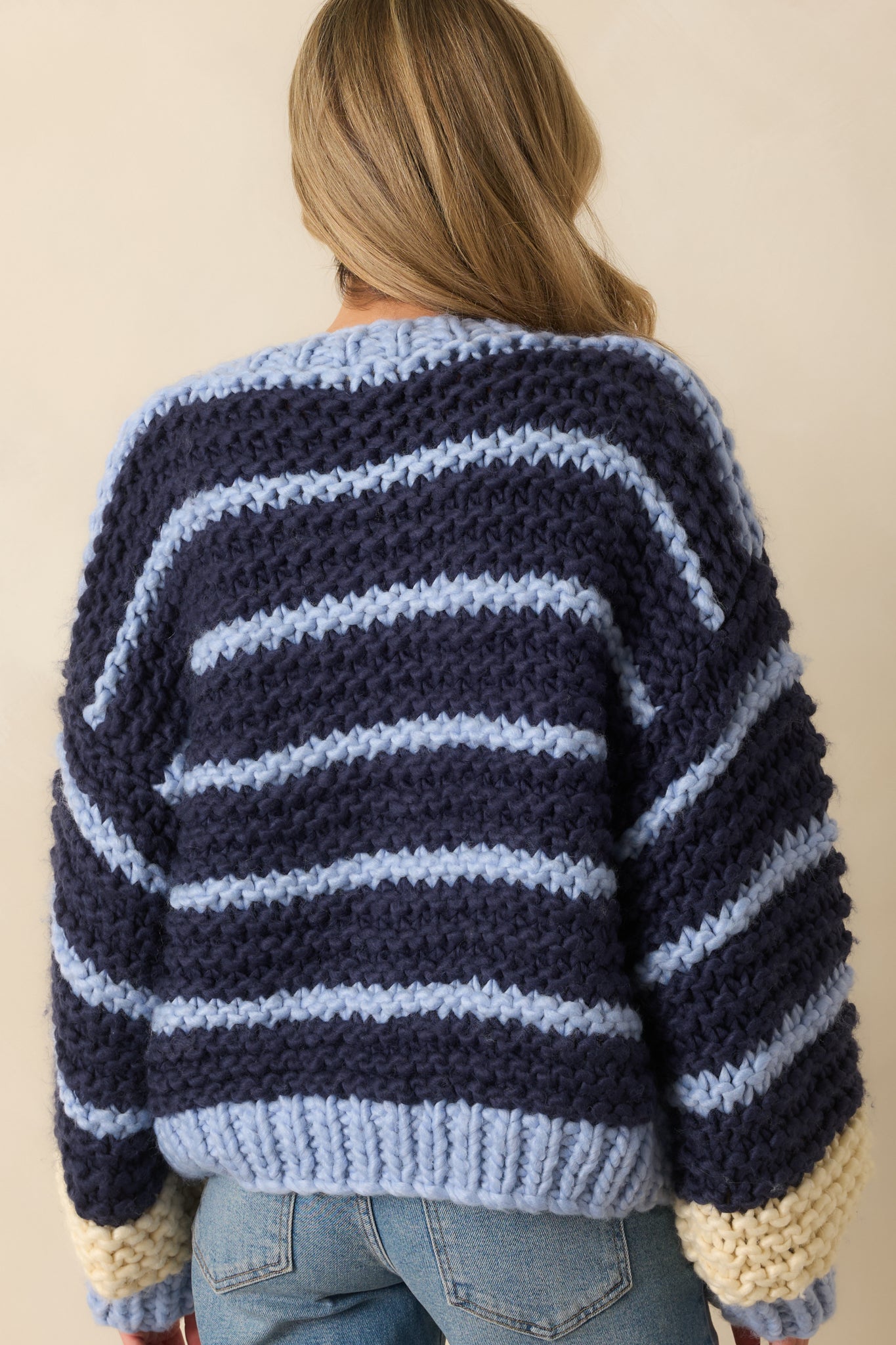 Rear view of the navy chunky knit cardigan featuring long sleeves, relaxed fit, and horizontal stripe pattern.