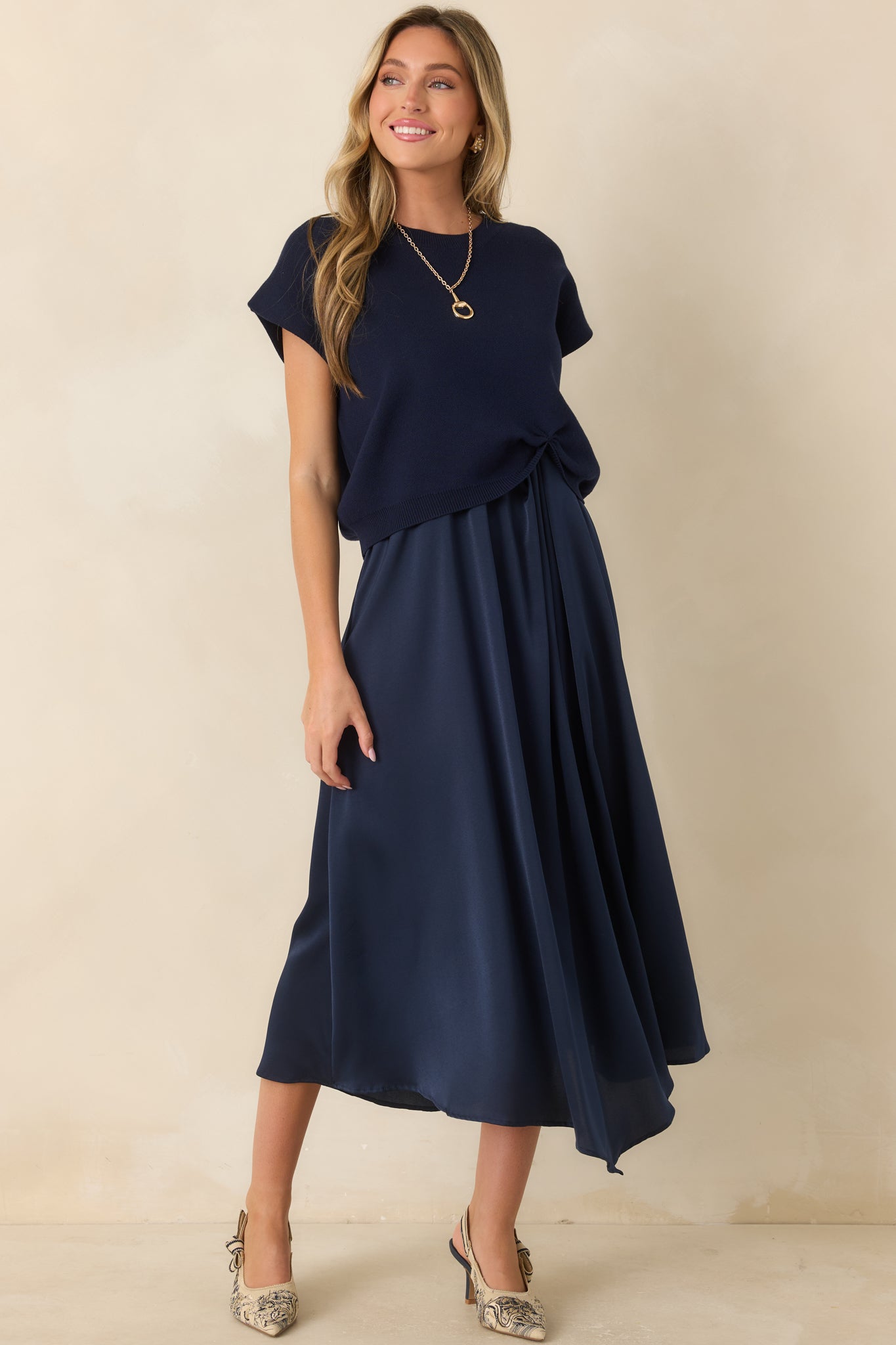 Navy cotton-blend sweater designed with cap sleeves, a relaxed silhouette, ribbed neckline, and an eye-catching cinched hem.