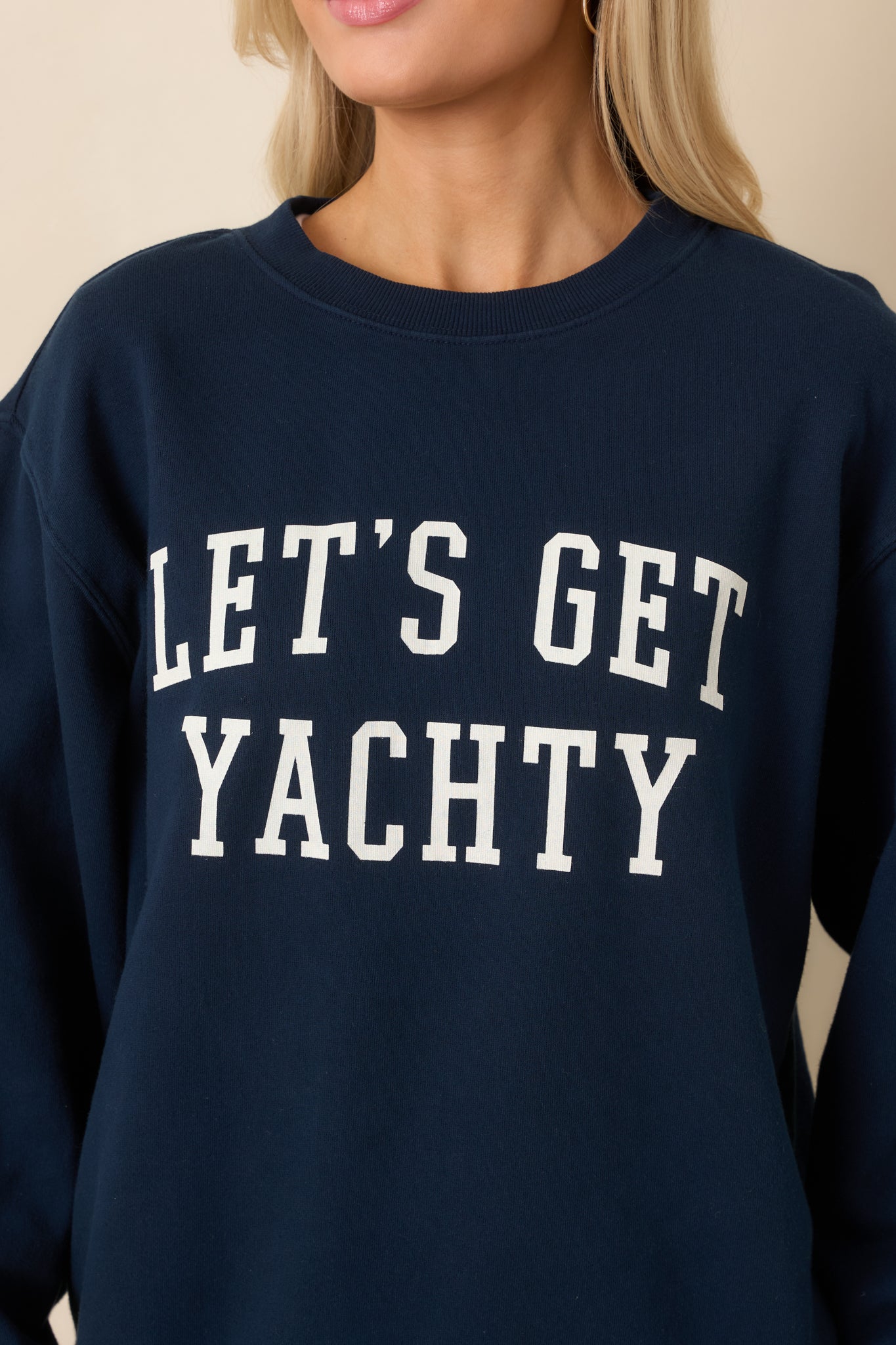 Close-up of navy cotton sweatshirt displaying “Let’s Get Yachty” graphic and ribbed neckline texture.